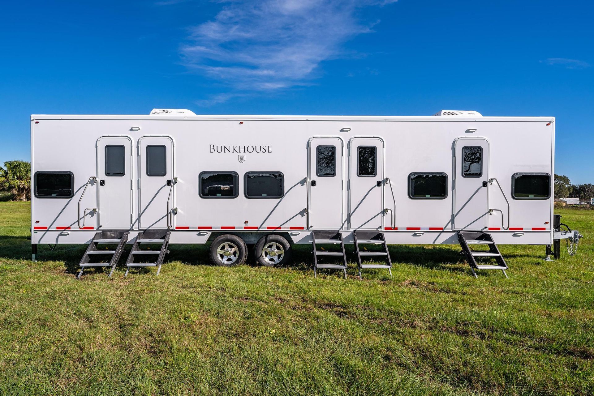 A white trailer is parked in a grassy field