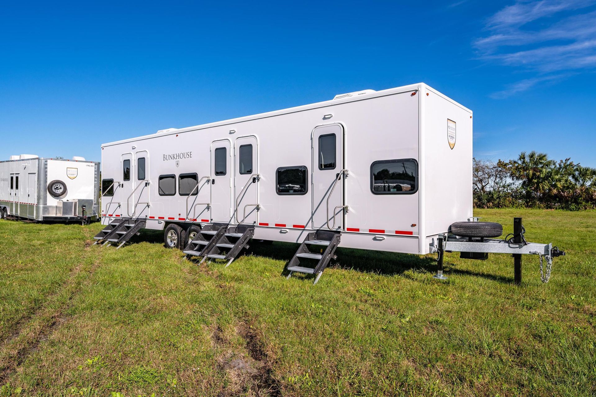 A row of trailers are parked in a grassy field