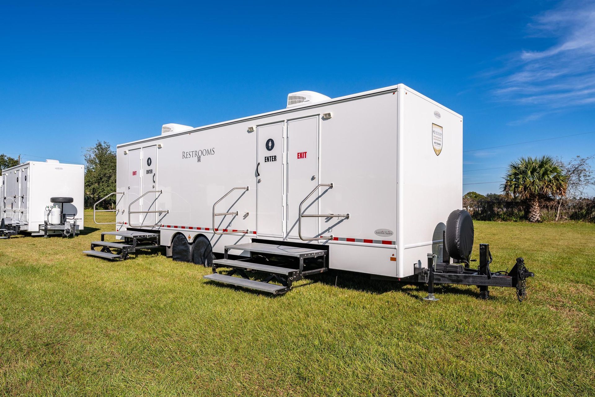 A row of white trailers are parked in a grassy field