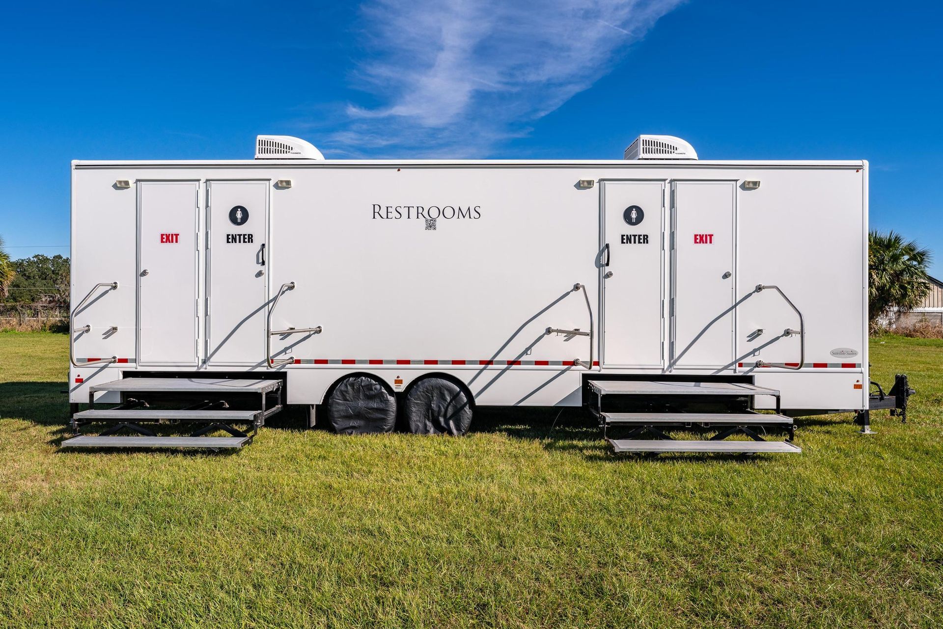 A white trailer is parked in a grassy field
