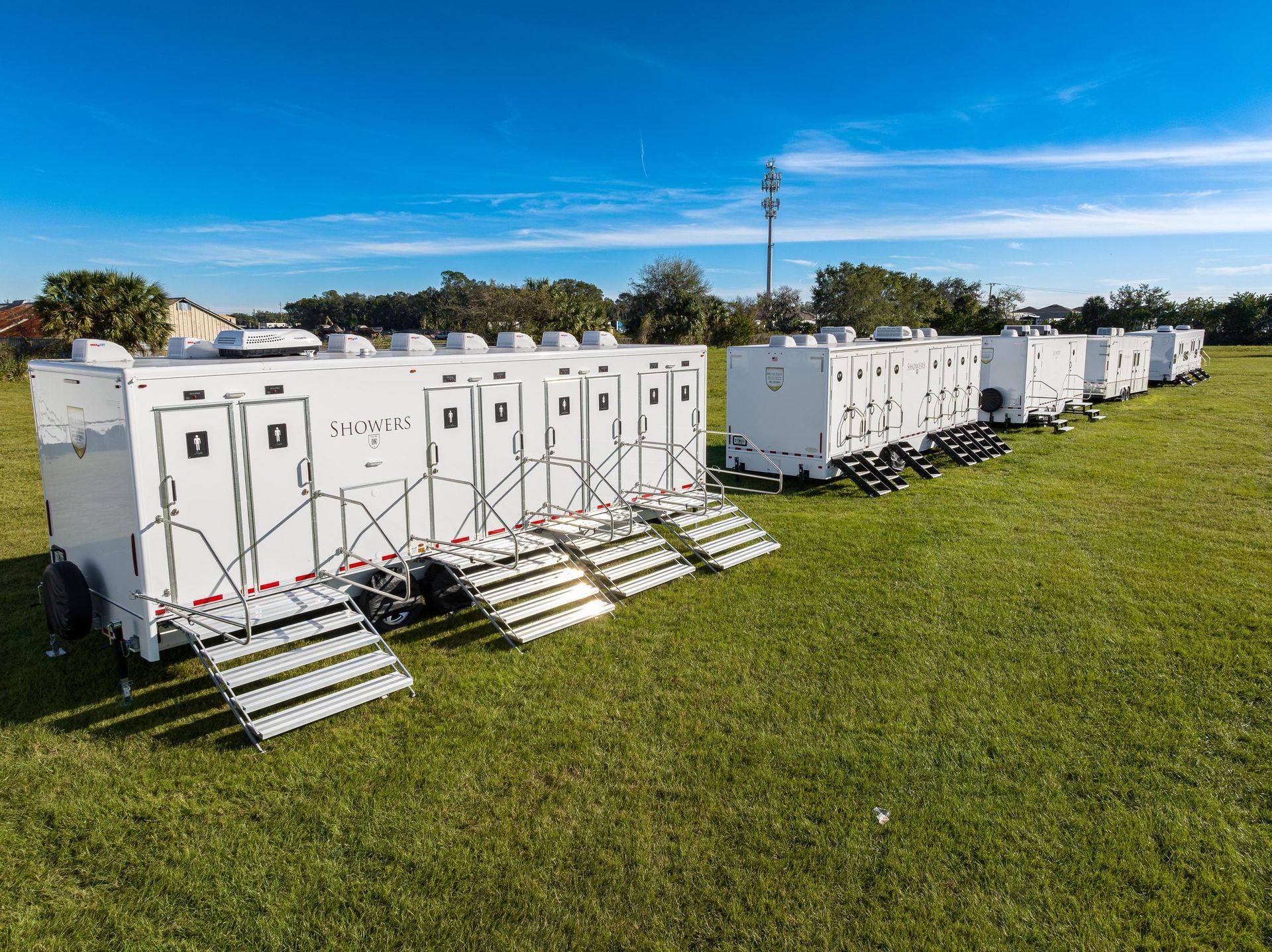 A row of white trailers sitting on top of a lush green field