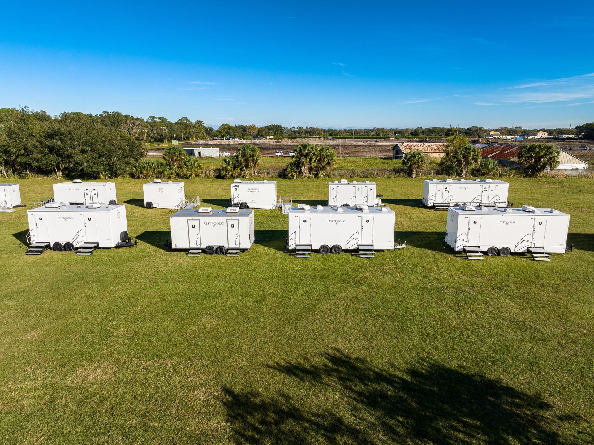 A row of white trailers are parked in a grassy field