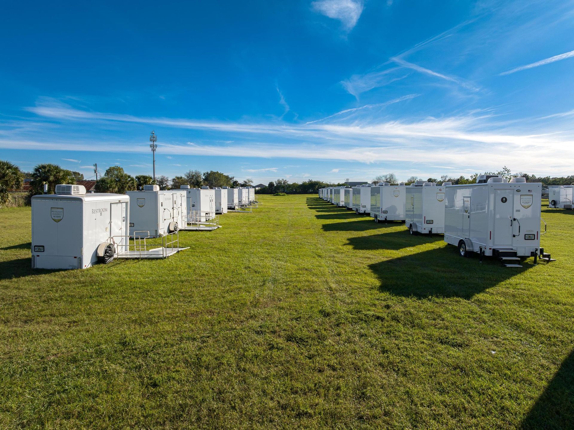 A row of white trailers are parked in a grassy field