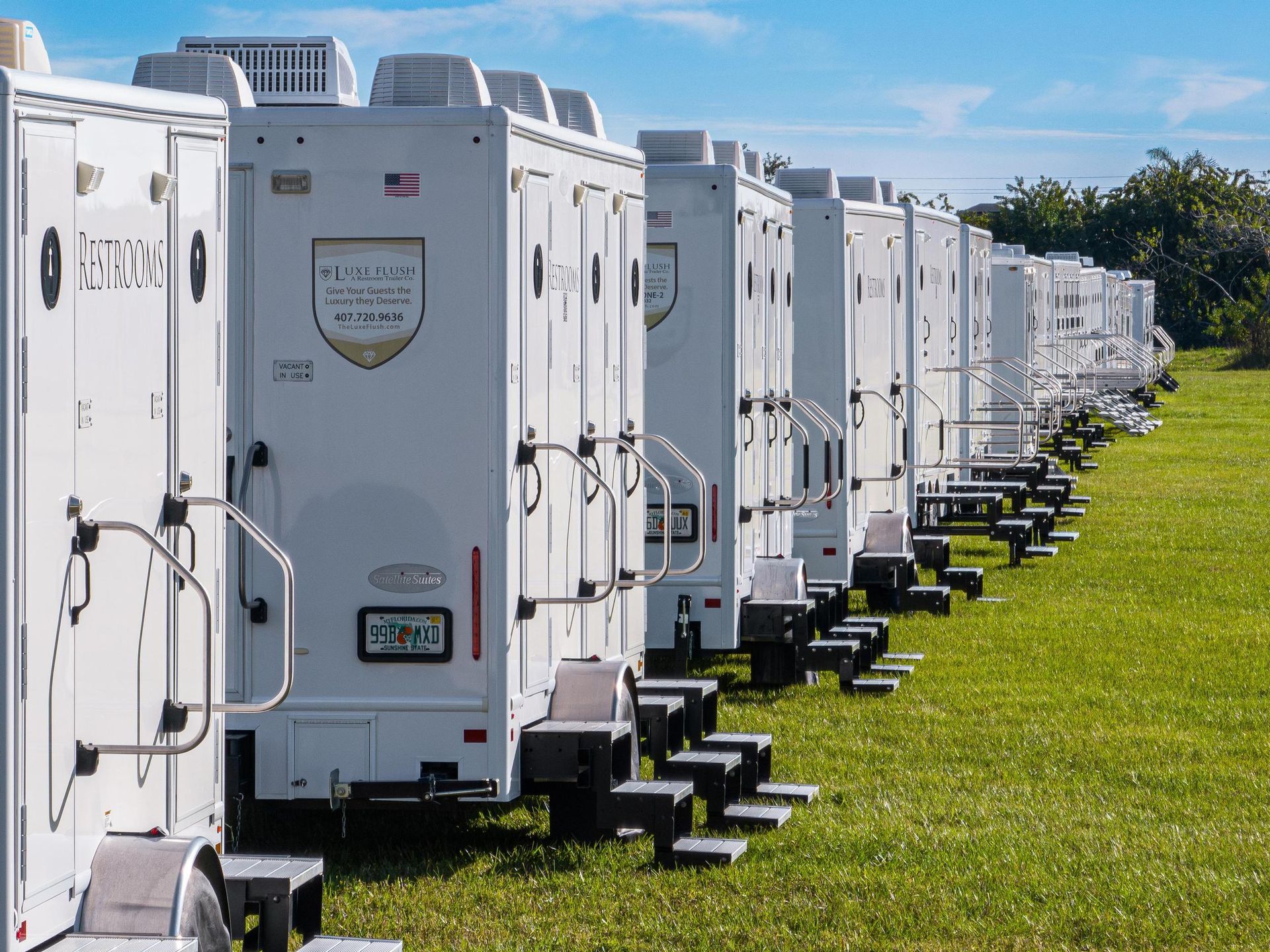 A row of white trailers are parked in a grassy field