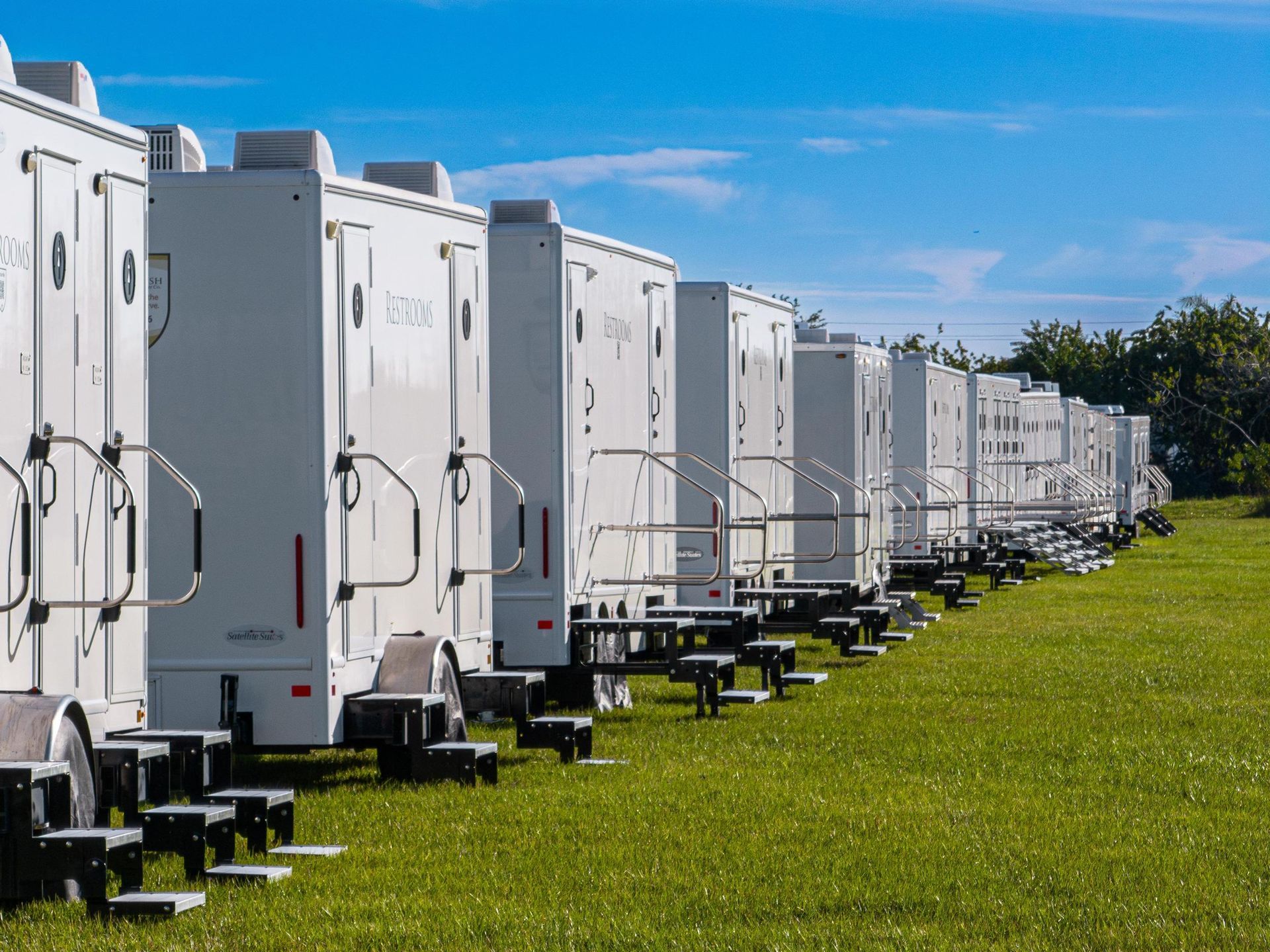 A row of white trailers are parked in a grassy field
