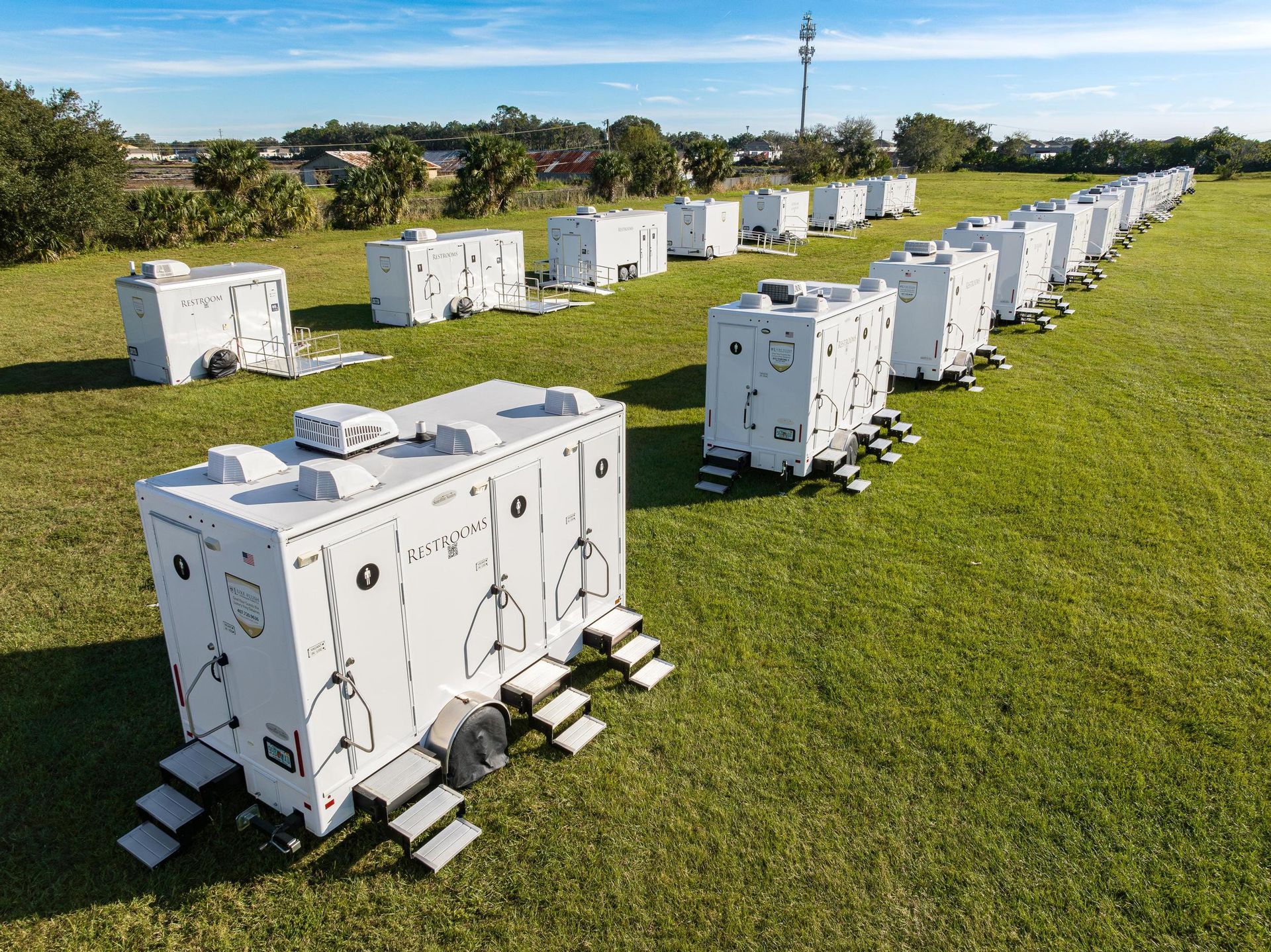A row of white trailers sitting on top of a lush green field