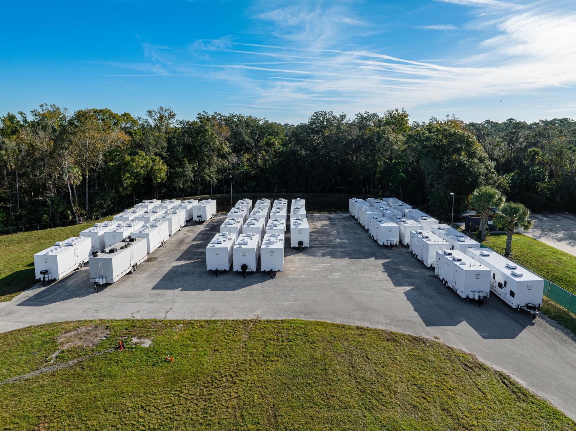 A row of white trailers are parked in a parking lot