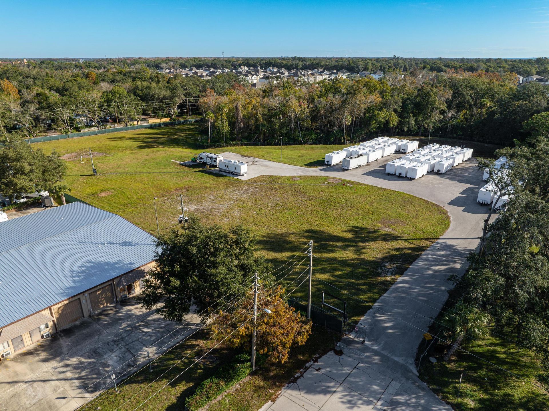 An aerial view of a large warehouse surrounded by trees and a road
