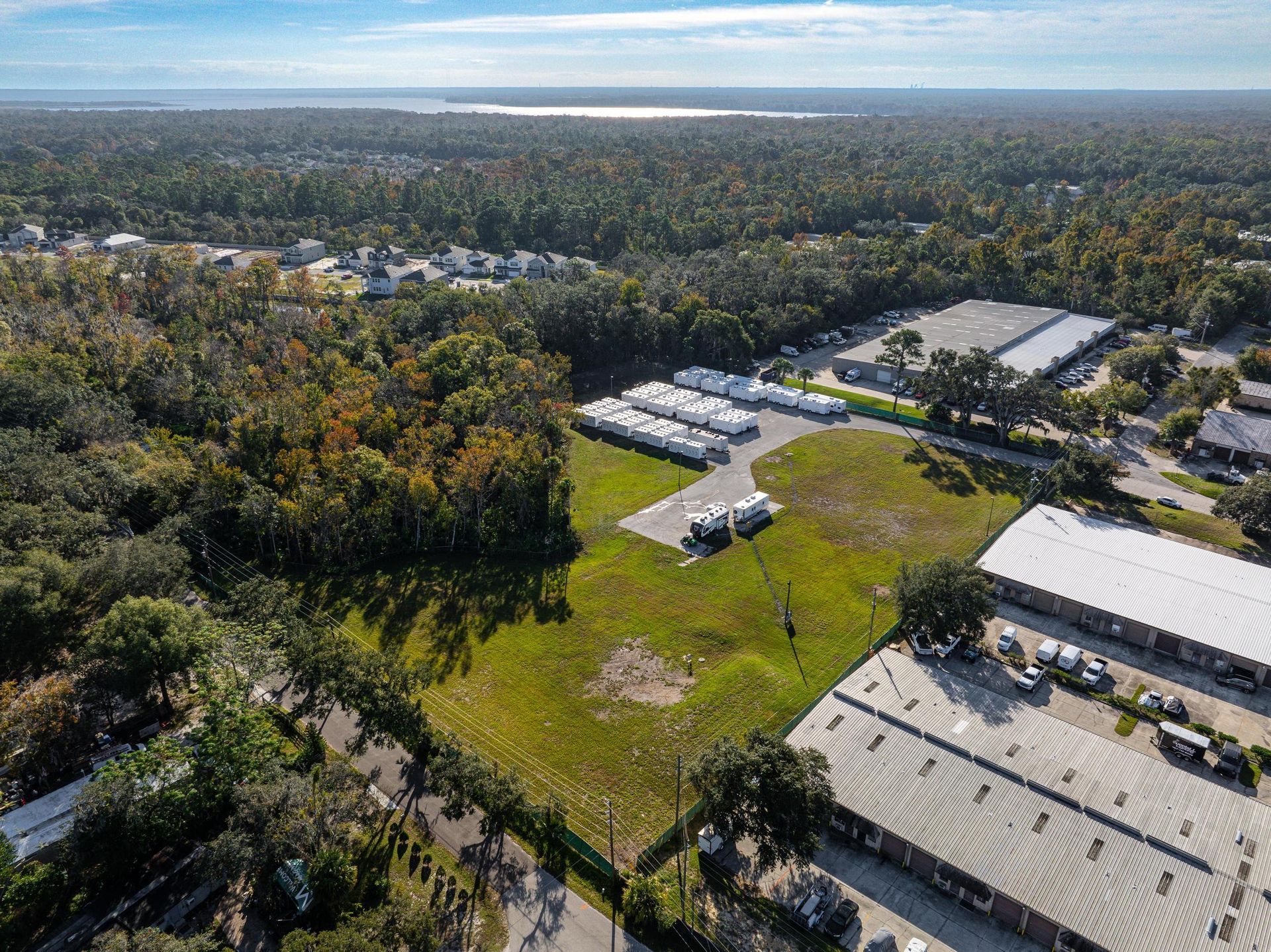 An aerial view of a large warehouse surrounded by trees and buildings