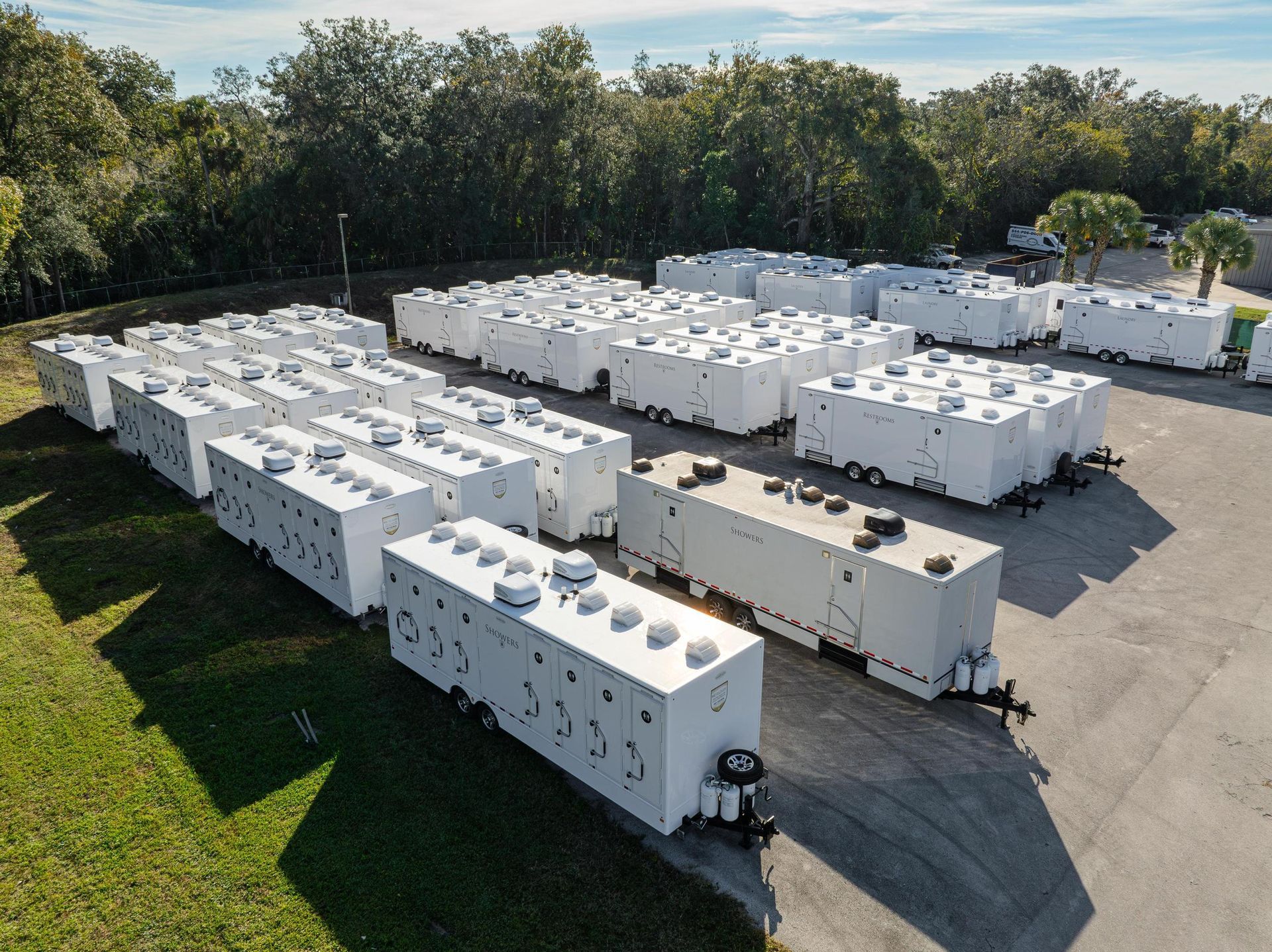 A bunch of white trailers are parked in a lo