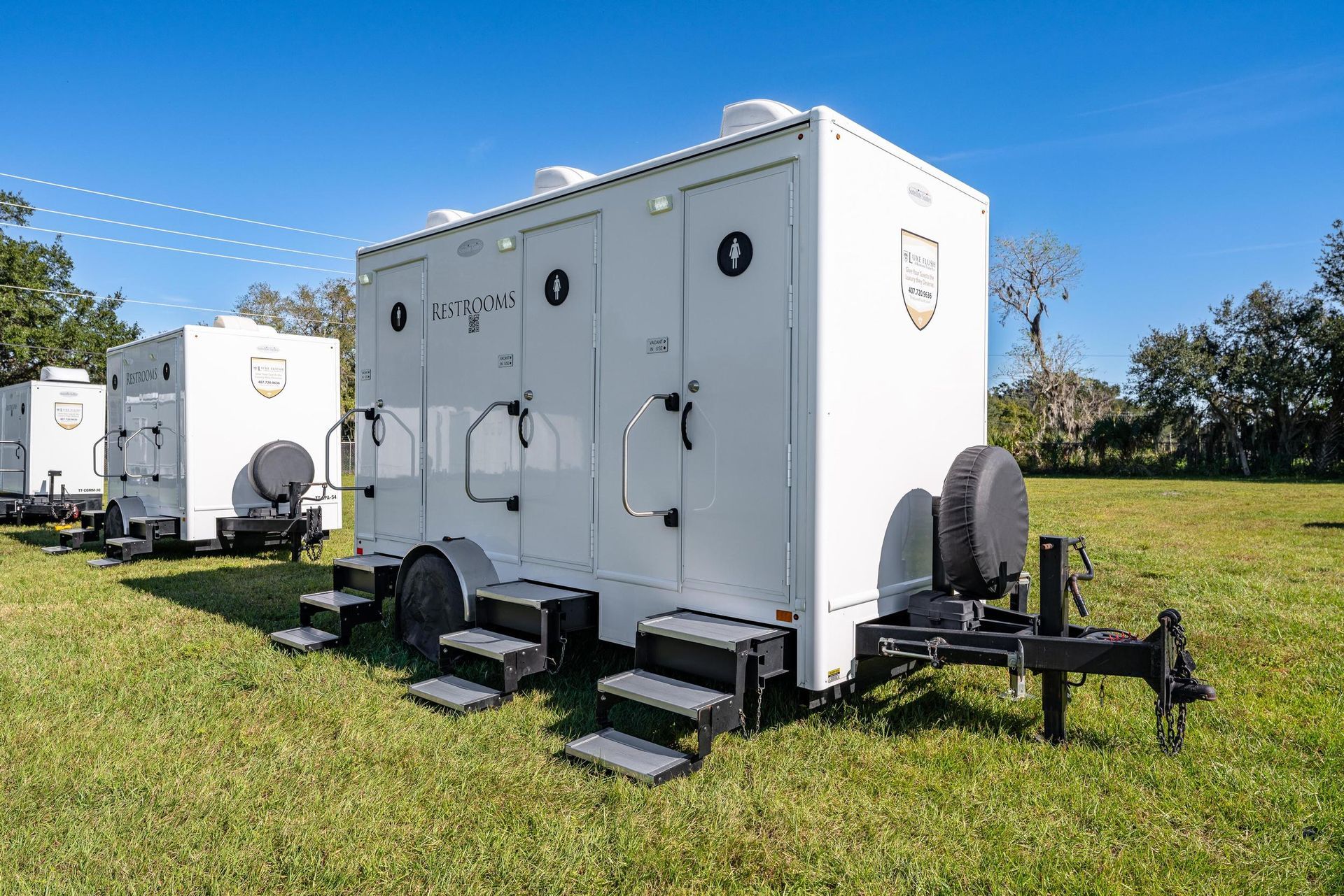A row of white trailers are parked in a grassy field