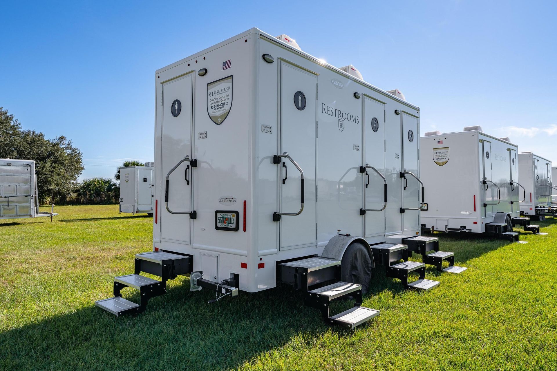 A row of white trailers are parked in a grassy field