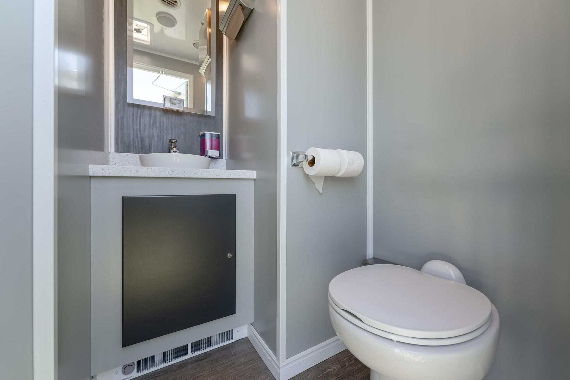 A bathroom with a toilet, sink, and mirror