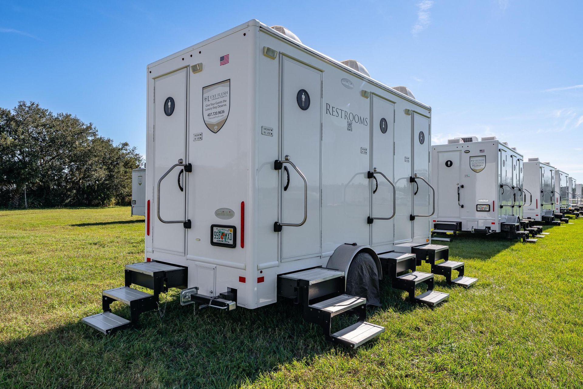 A row of white trailers are parked in a grassy field