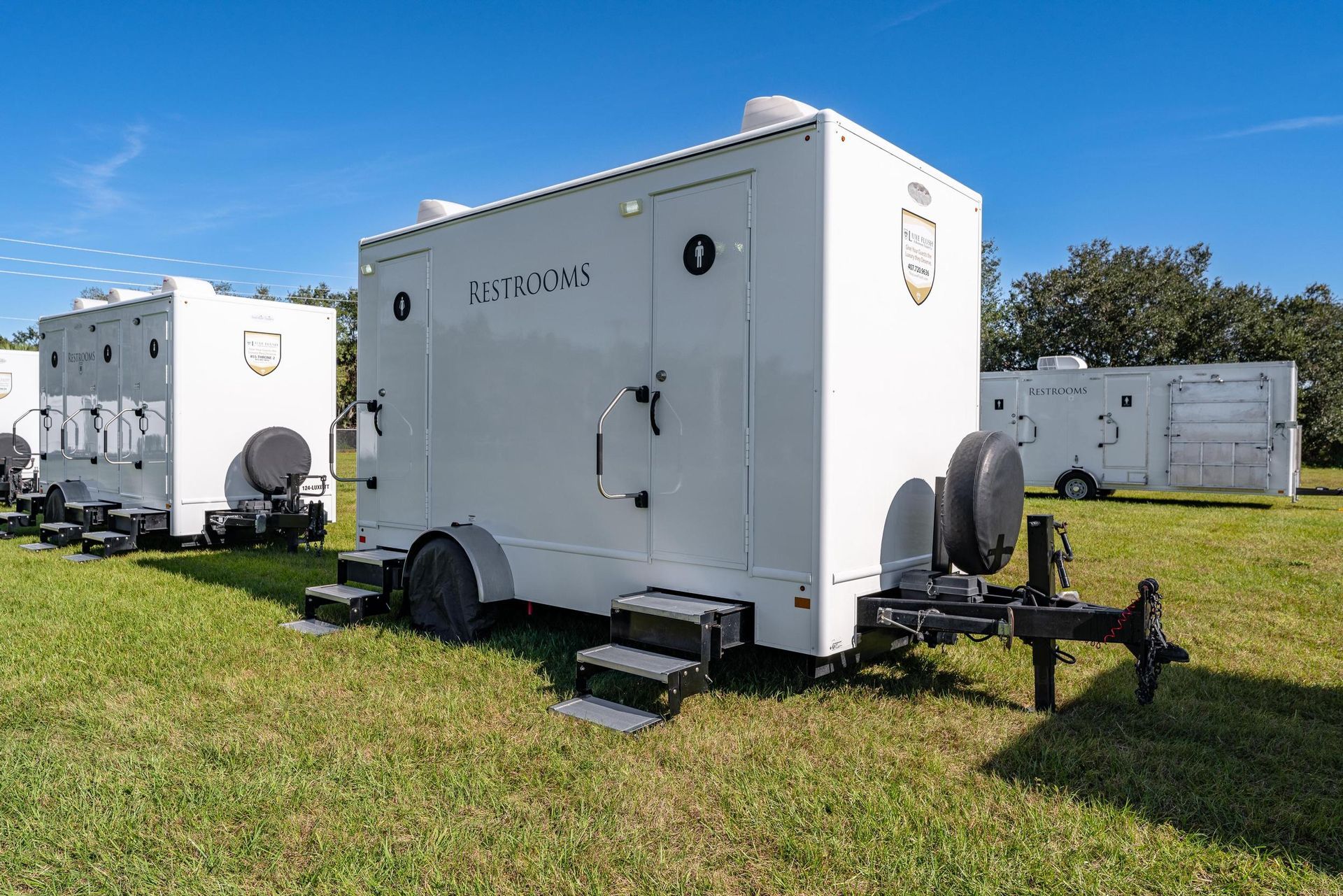 A row of white trailers are parked in a grassy field