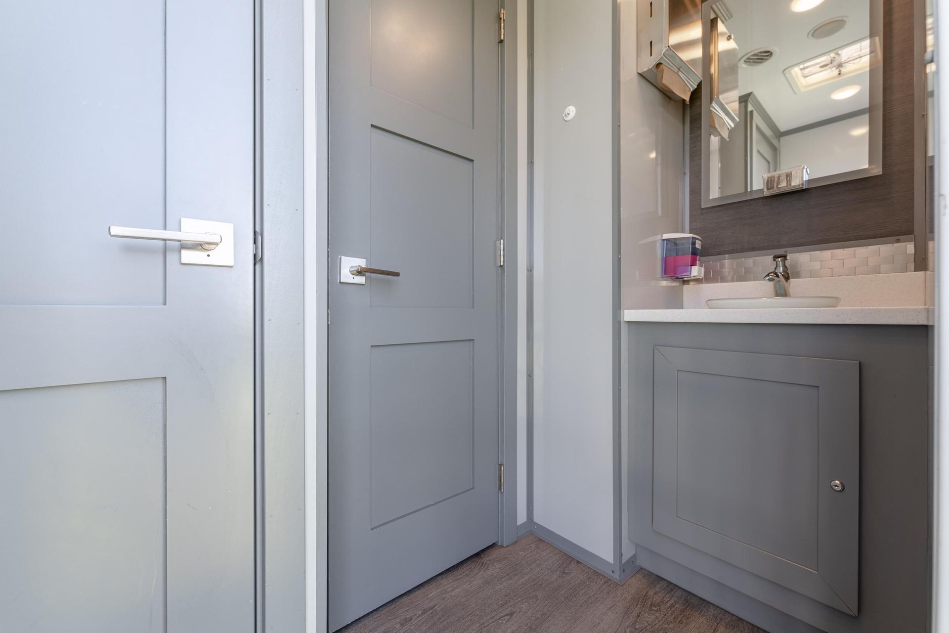 A bathroom with a sink, mirror, and door