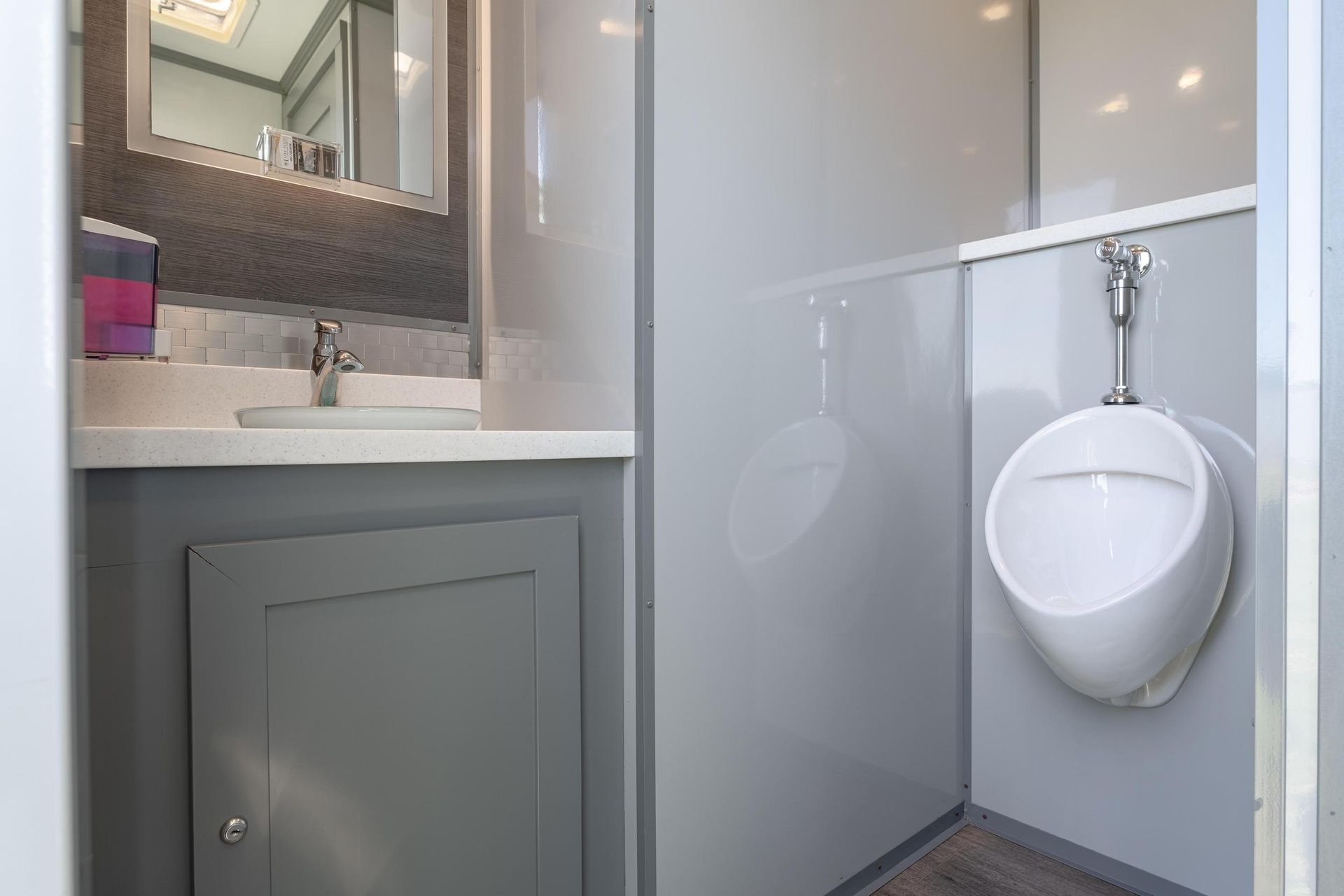 A bathroom with a urinal, sink, and mirror