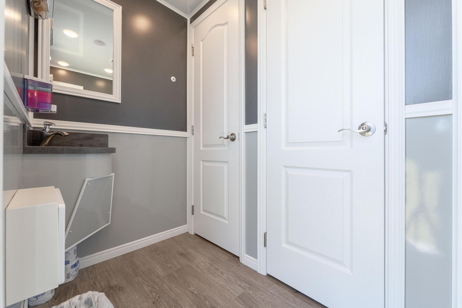 A bathroom with a sink, mirror, and door