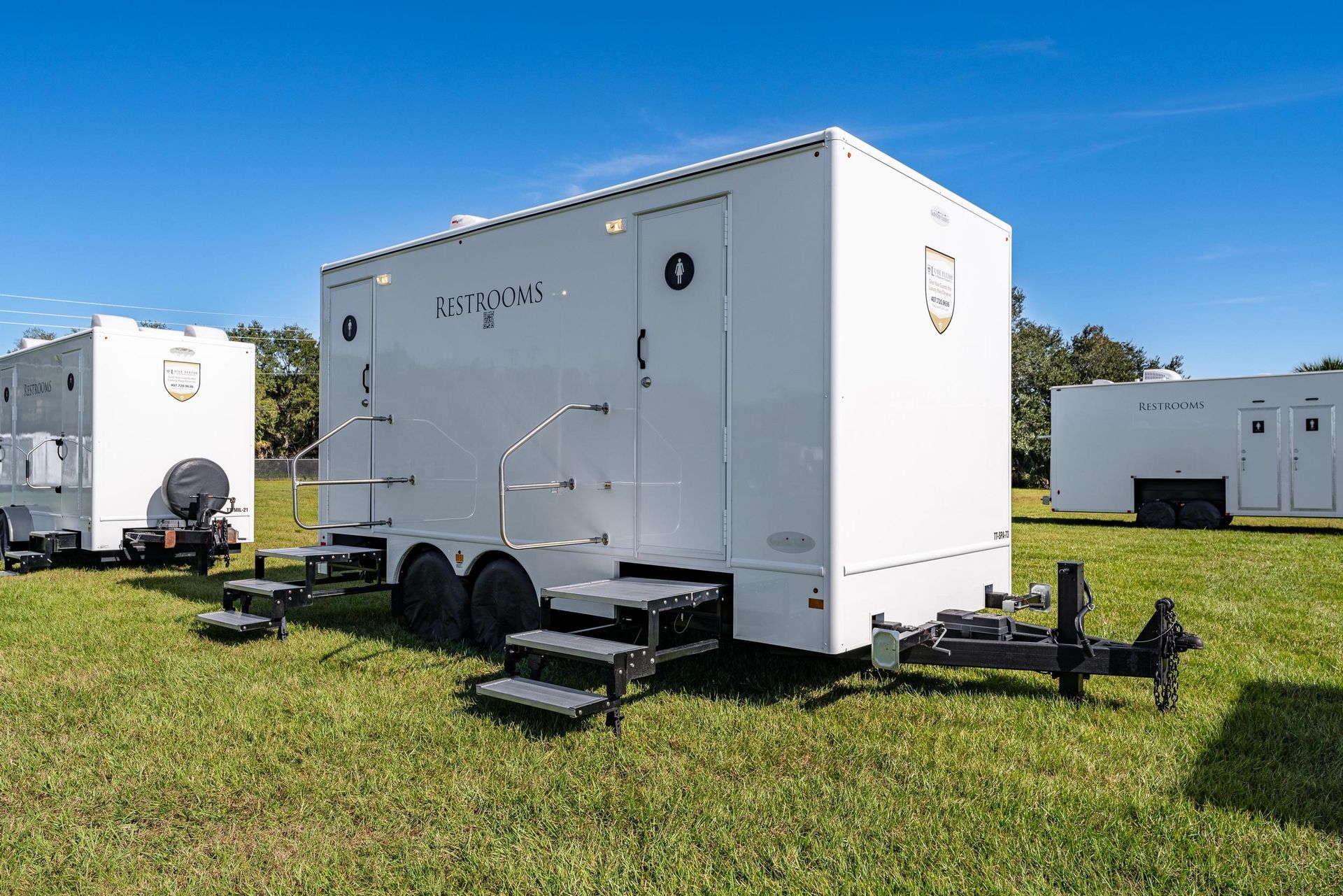 A row of white trailers are parked in a grassy field