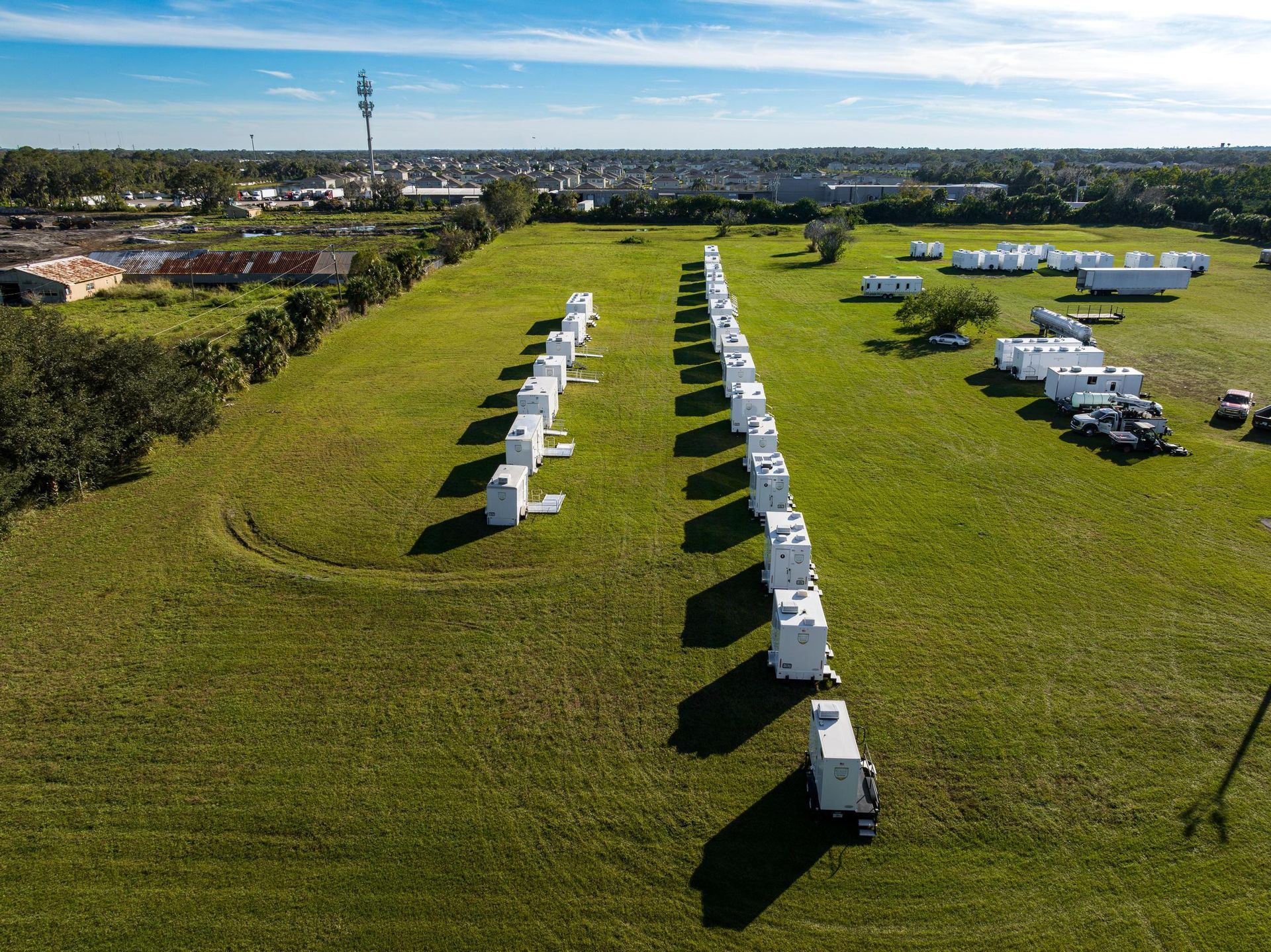 A row of white trailers are parked in a grassy field