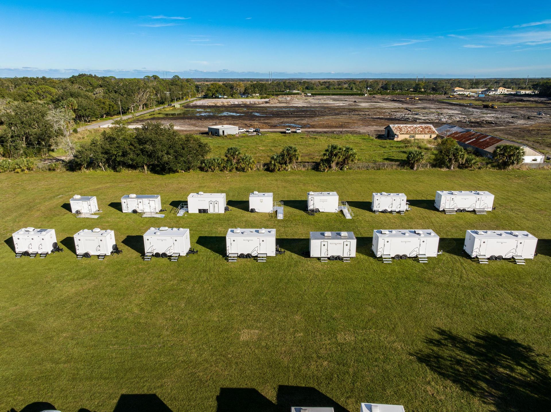 A row of trailers are parked in a grassy field