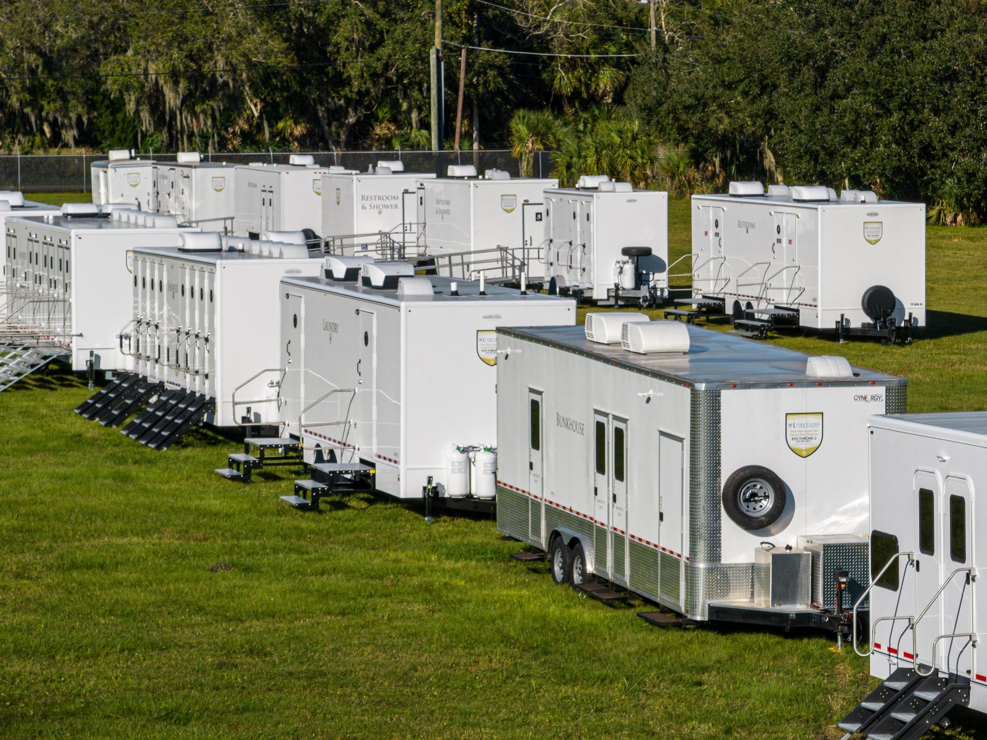 A row of trailers are parked in a grassy field