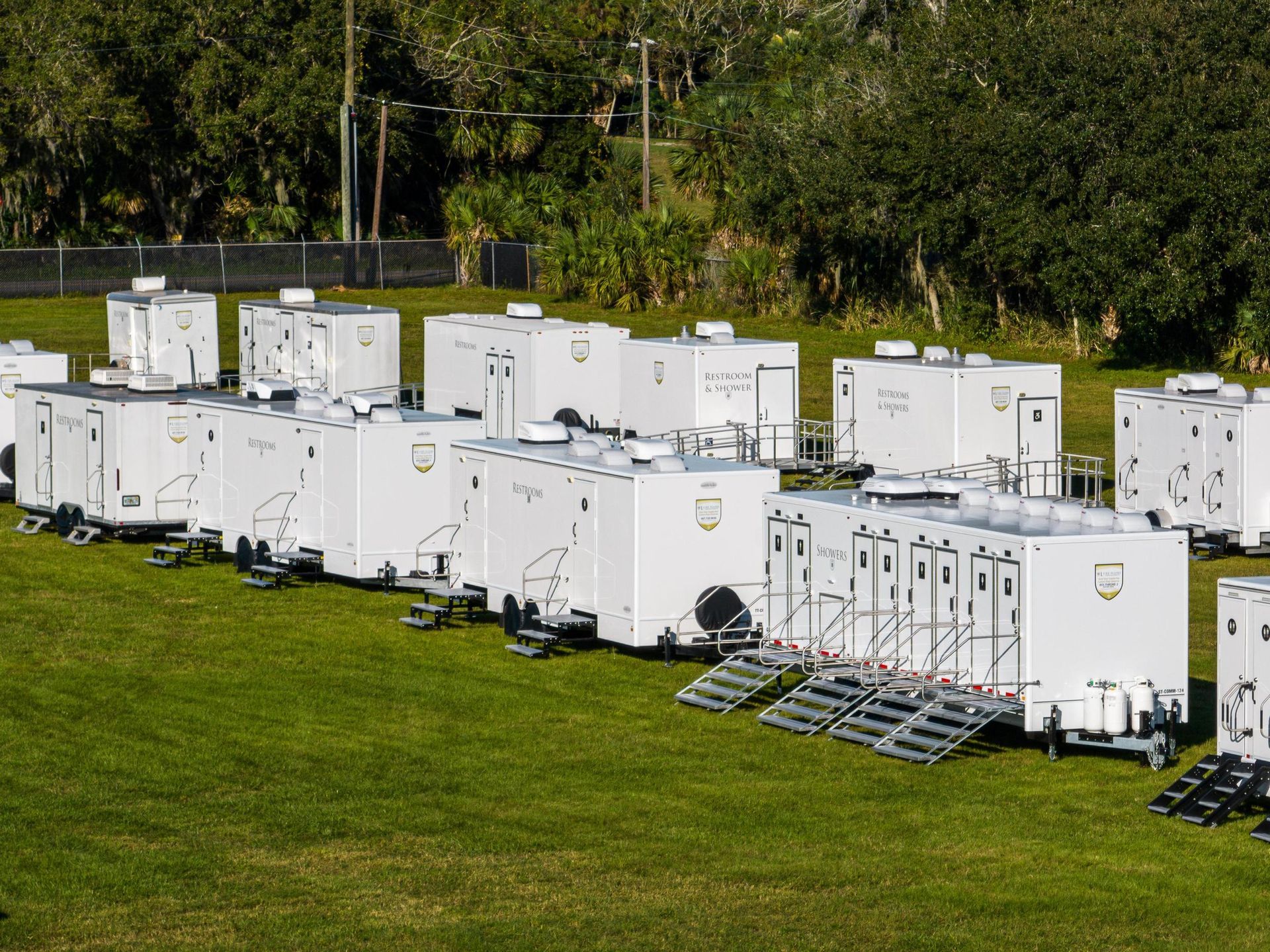 A row of white trailers are parked in a grassy field
