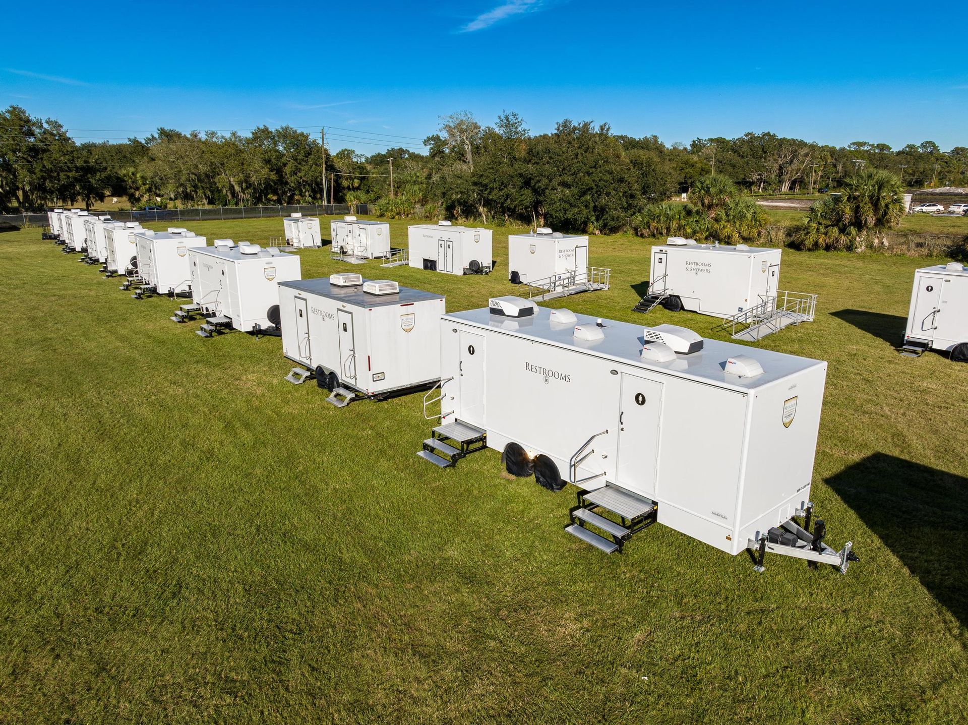 A row of white trailers are parked in a grassy field
