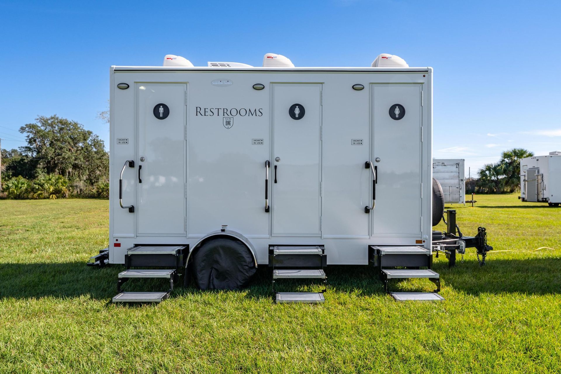A white trailer is parked in a grassy field