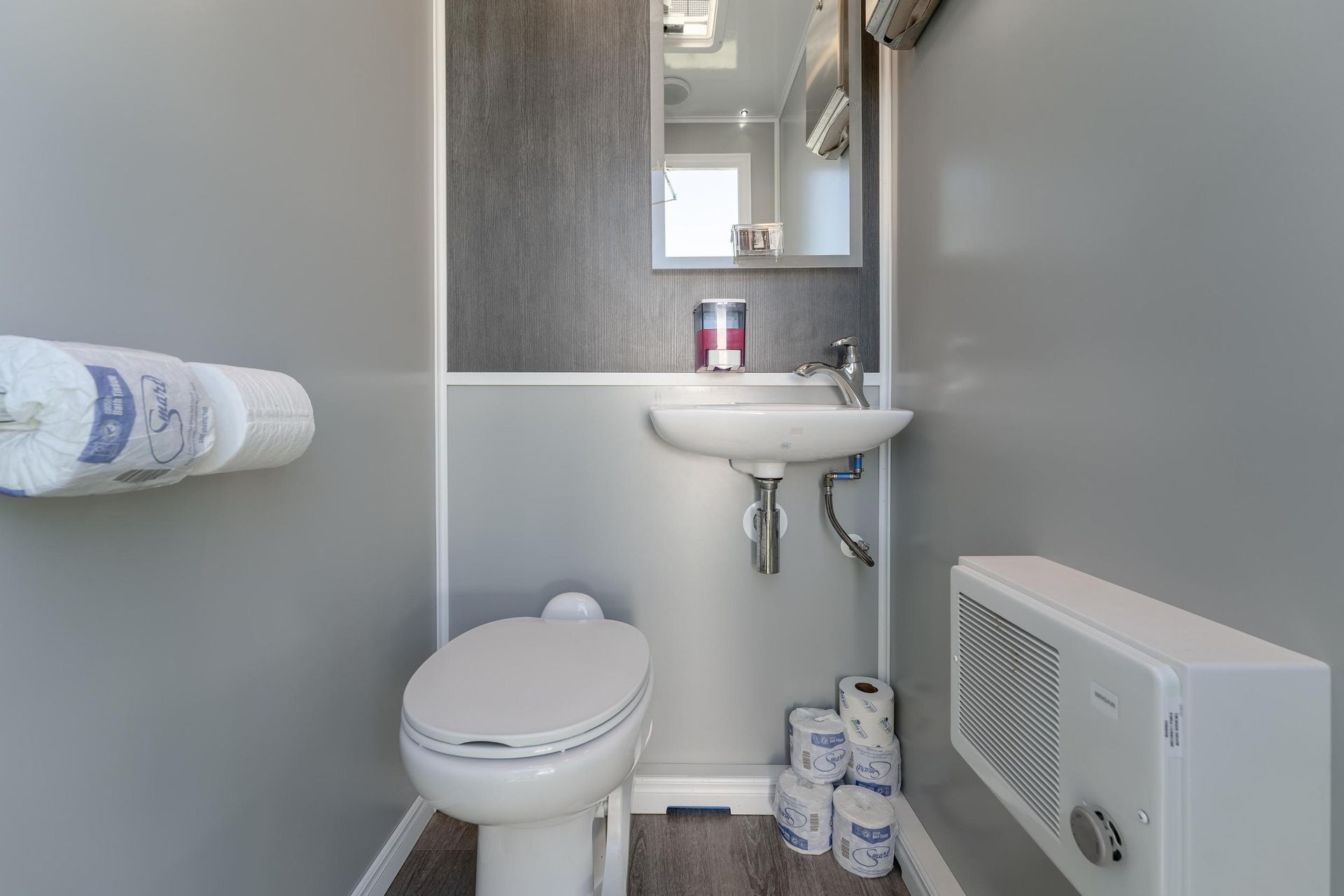 A bathroom with a toilet, sink, and mirror