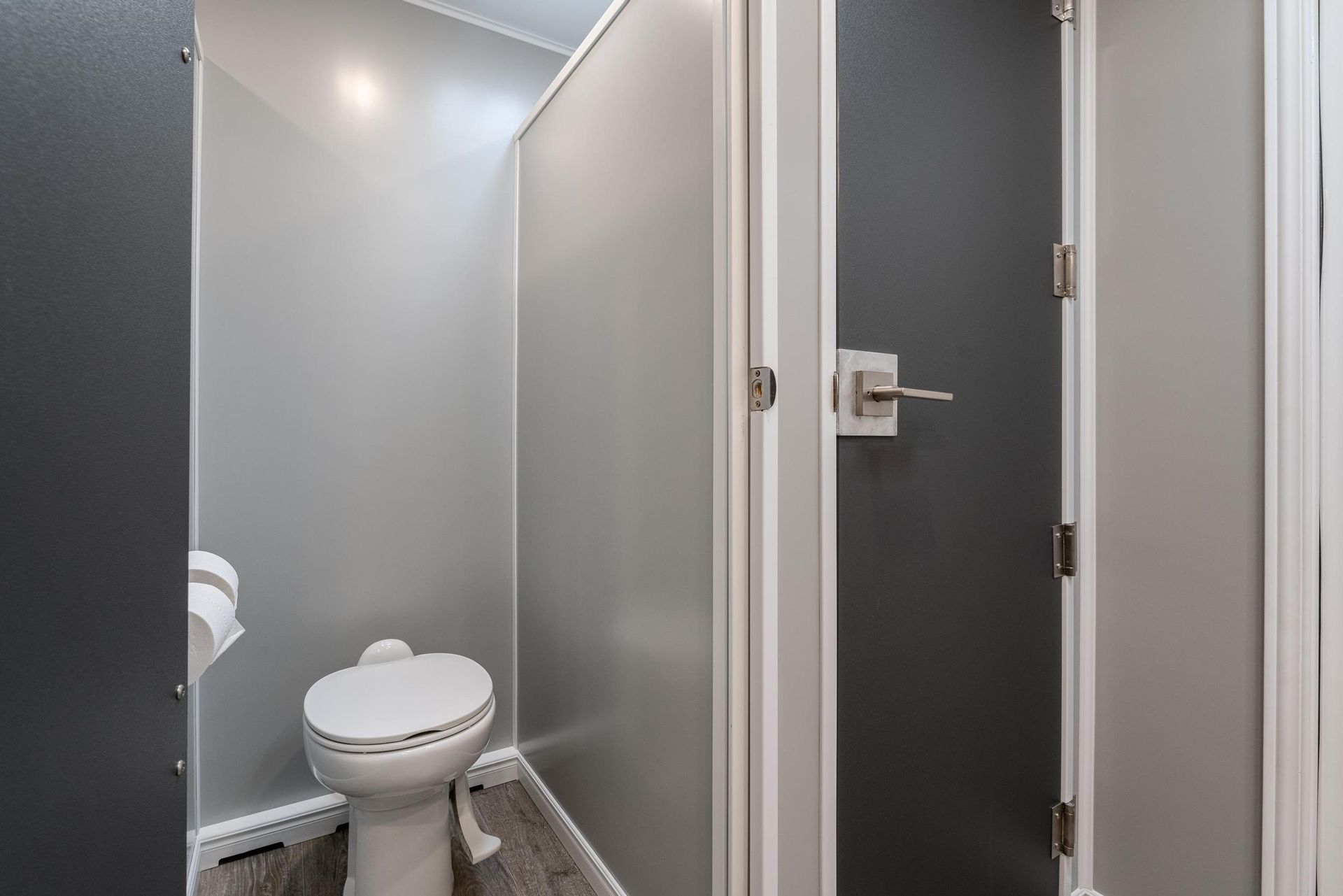A toilet is sitting in a bathroom between two doors