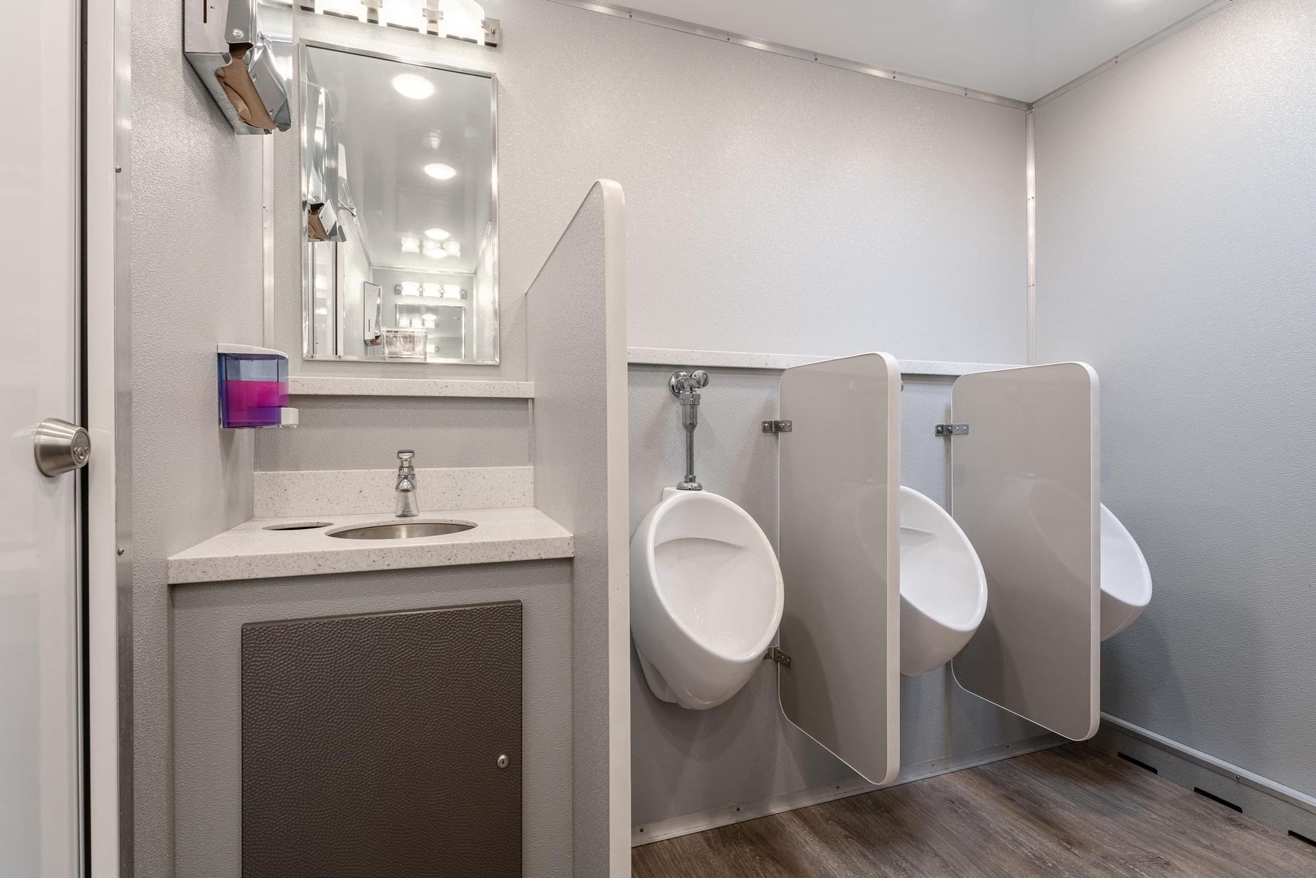 A bathroom with three urinals and a sink