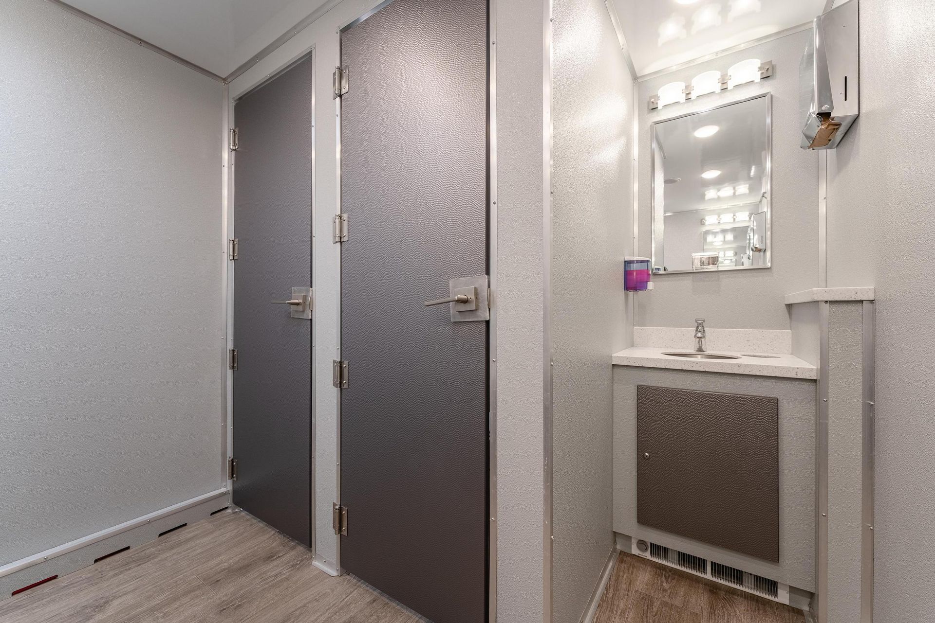 A bathroom with two stalls, a sink, and a mirror