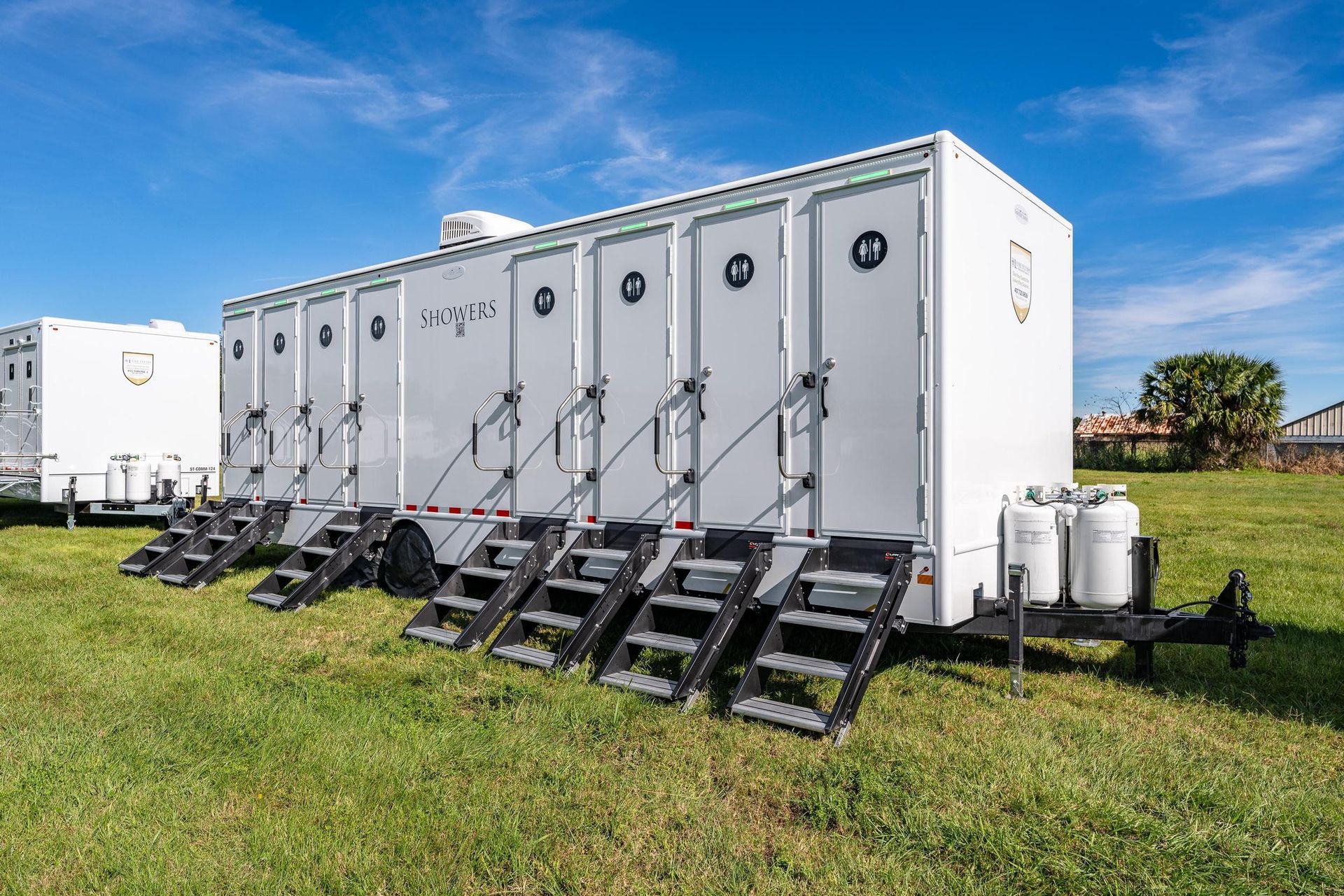 A row of portable toilets are lined up in a grassy field
