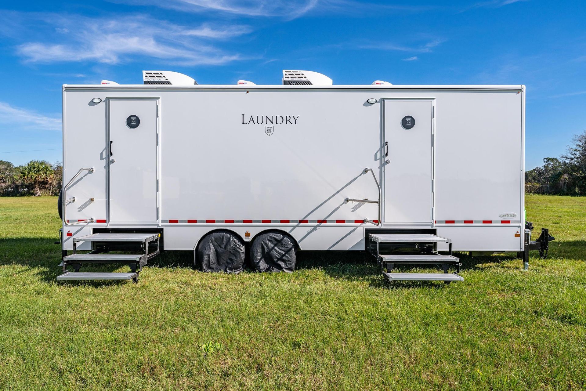 A white trailer is parked in a grassy field