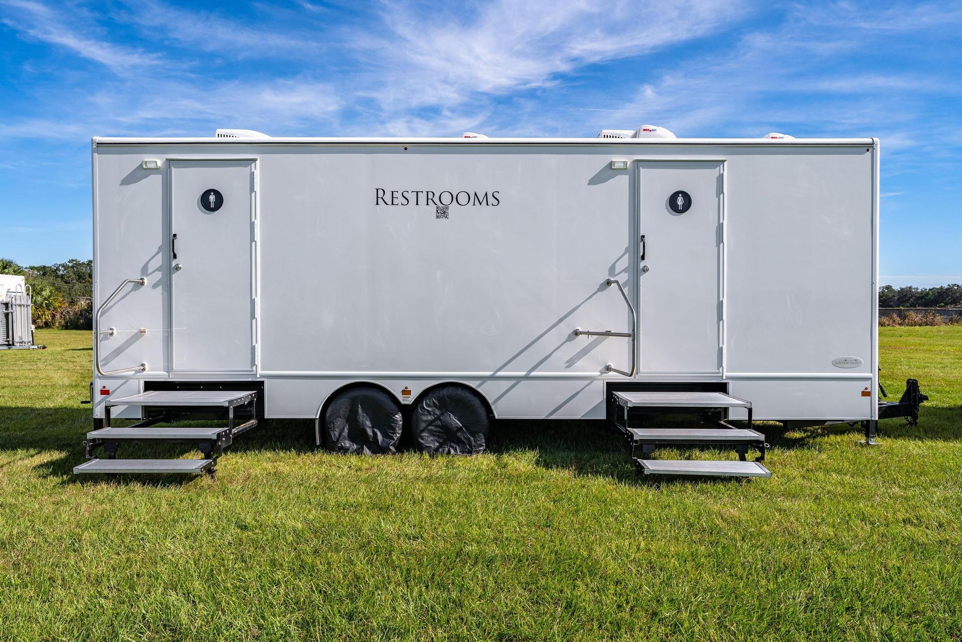 A white trailer is parked in a grassy field