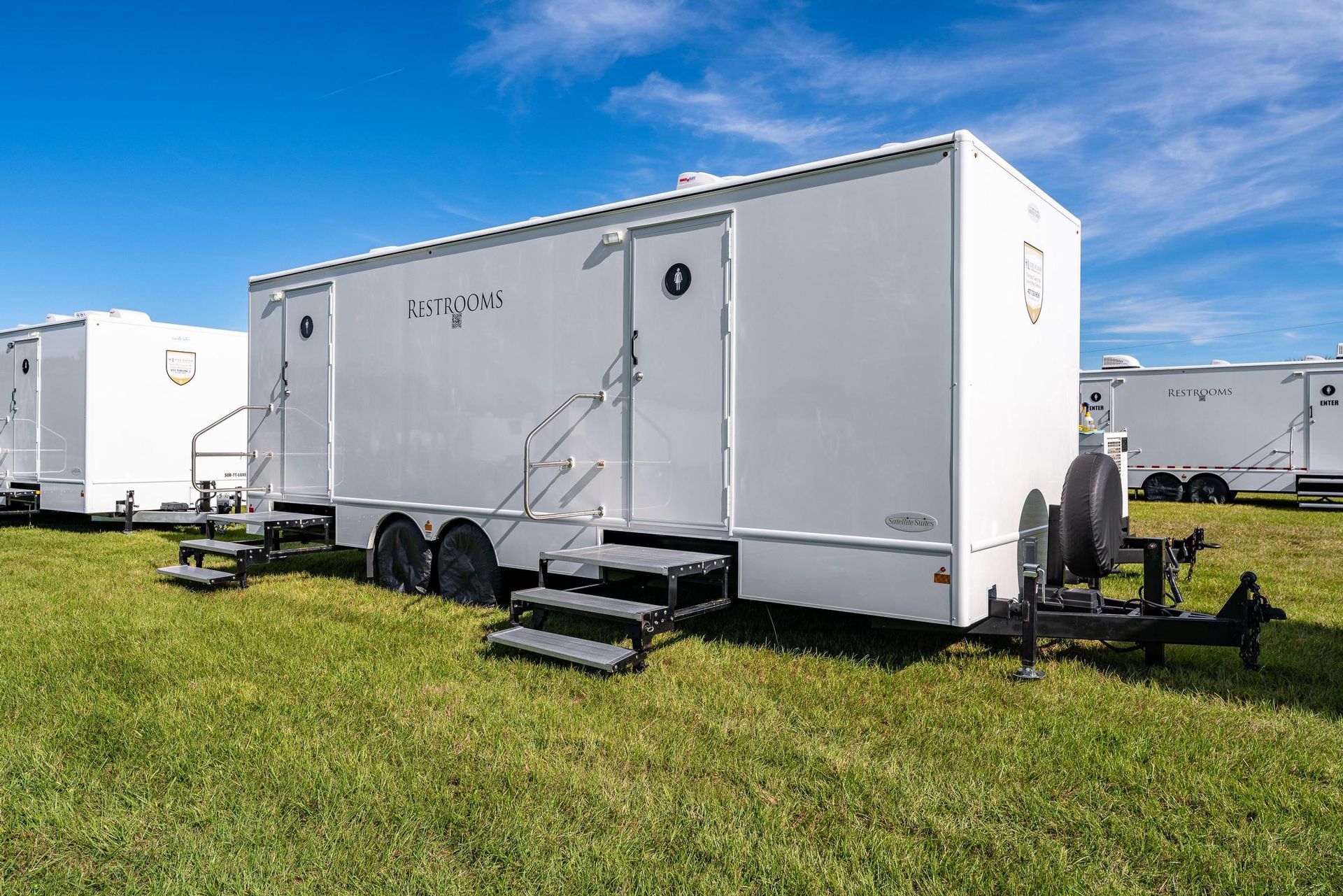 A row of white trailers are parked in a grassy field