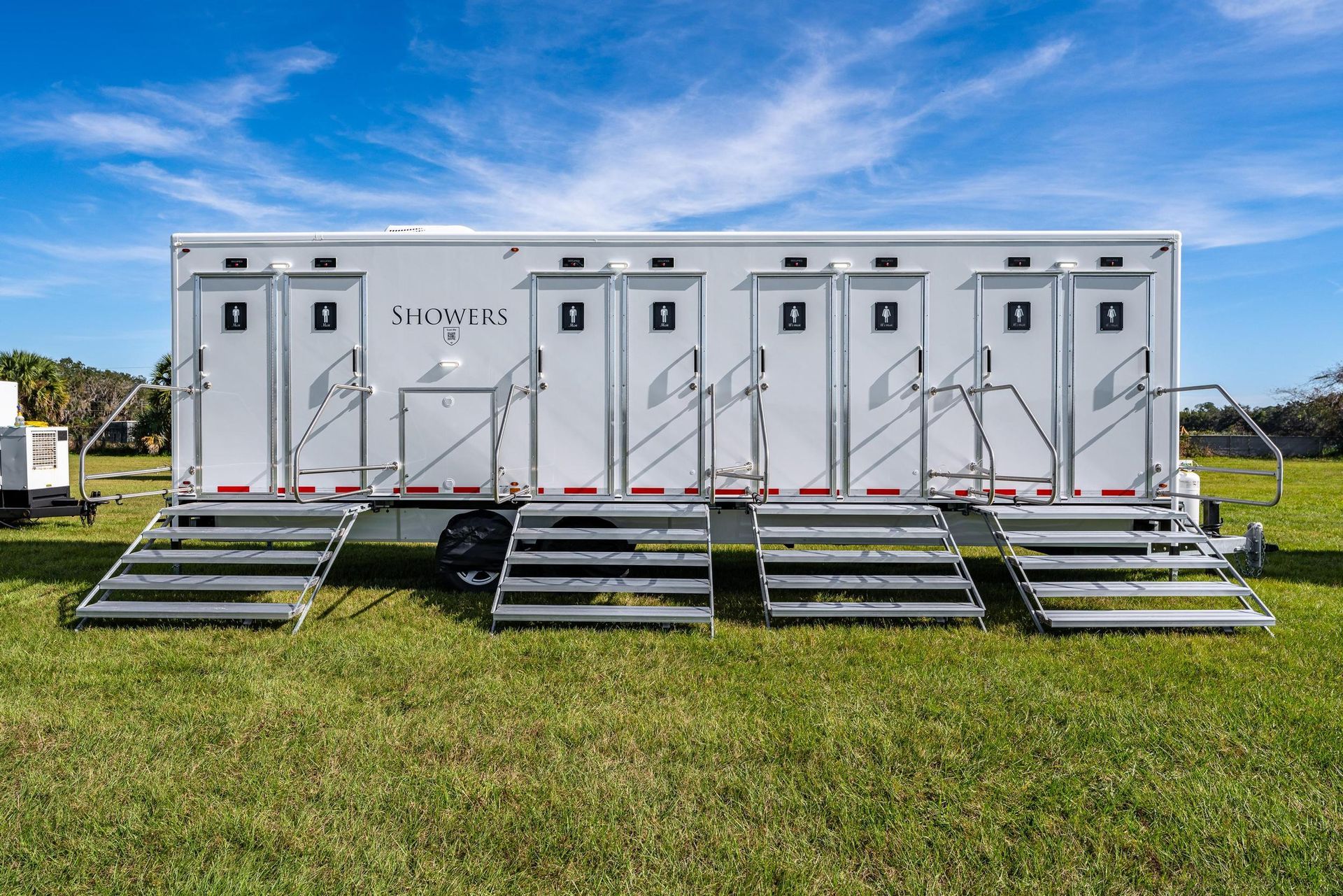 A trailer with a lot of doors and stairs is parked in a grassy field