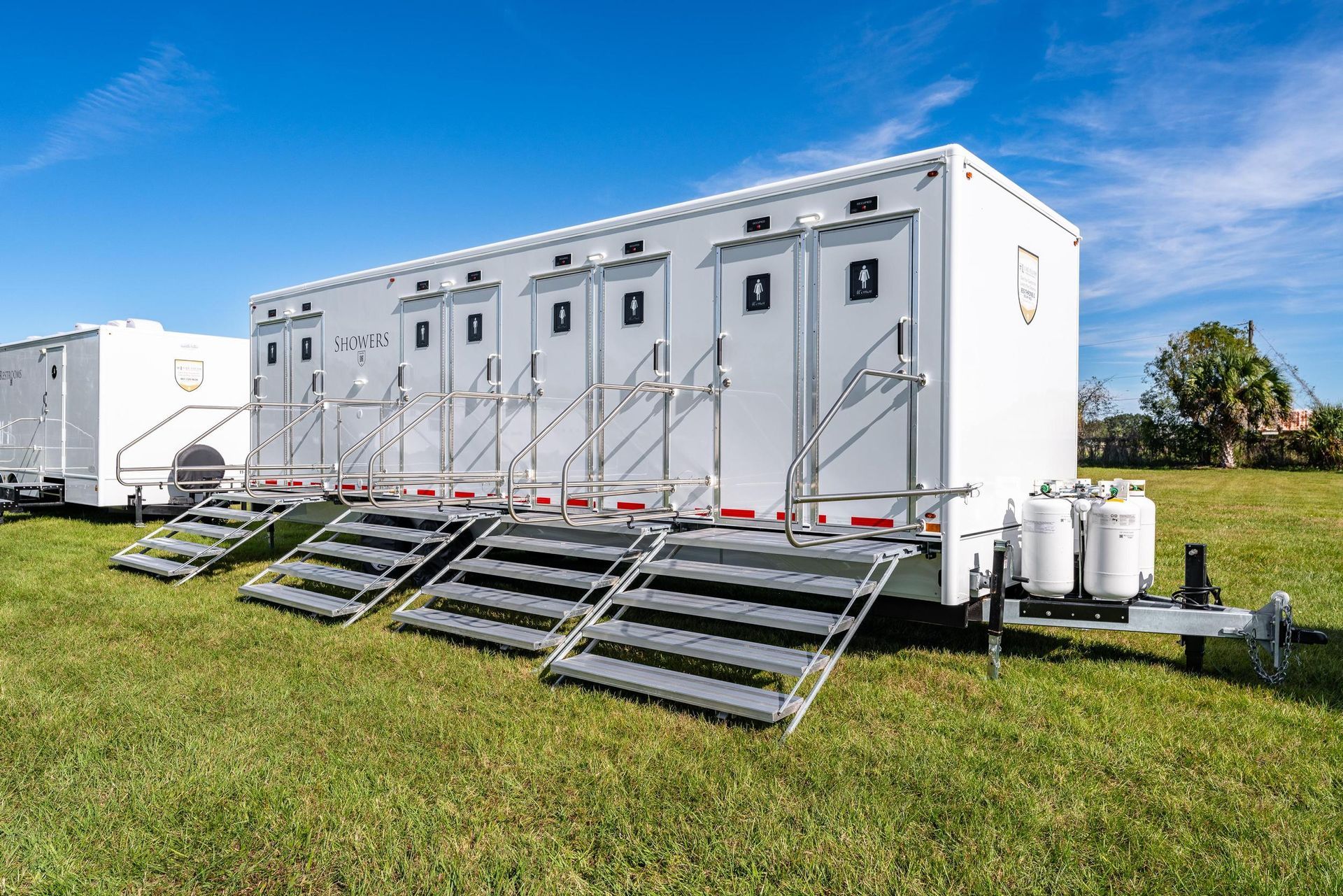 A row of white trailers are parked in a grassy field