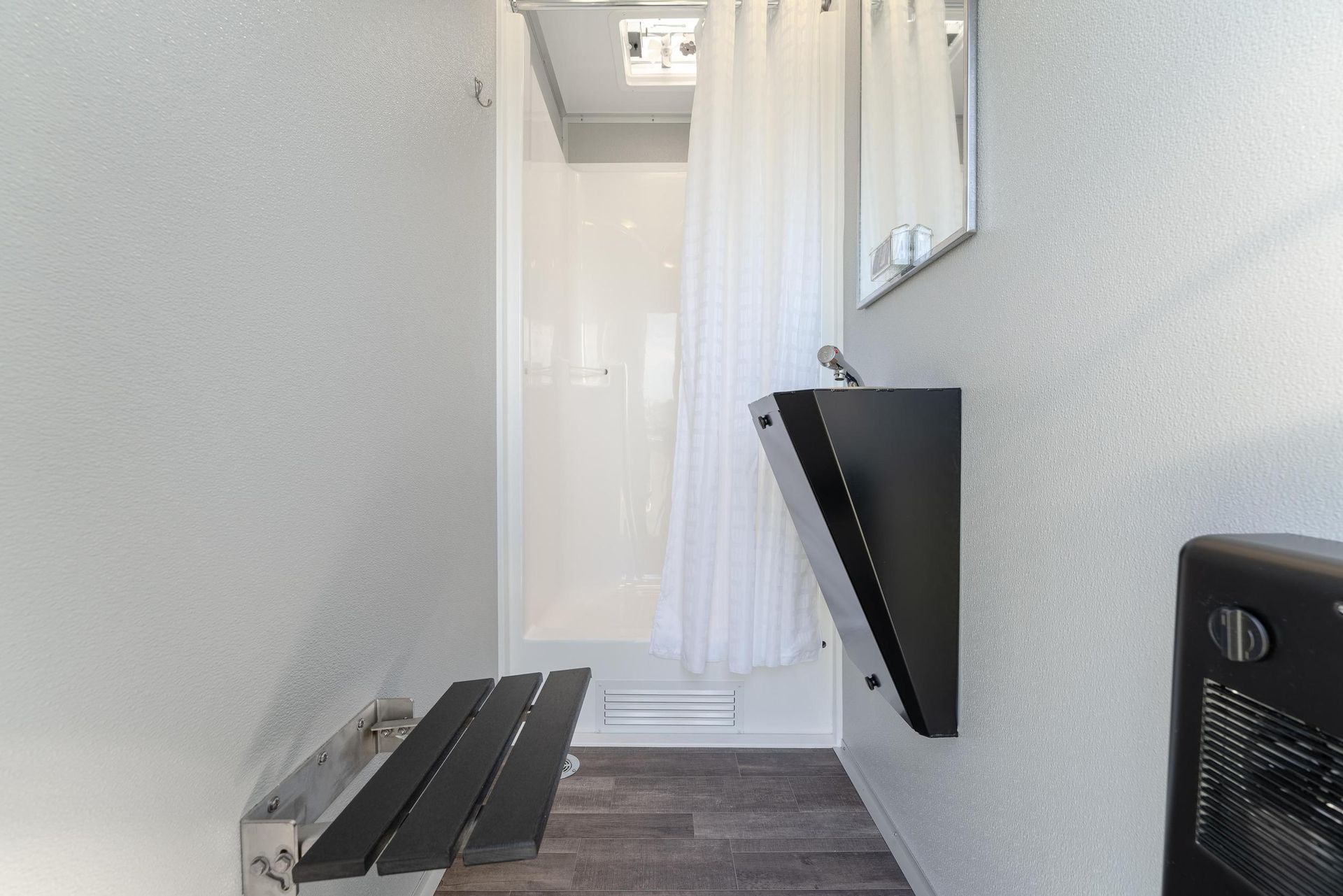 A bathroom with a sink, shower, and mirror