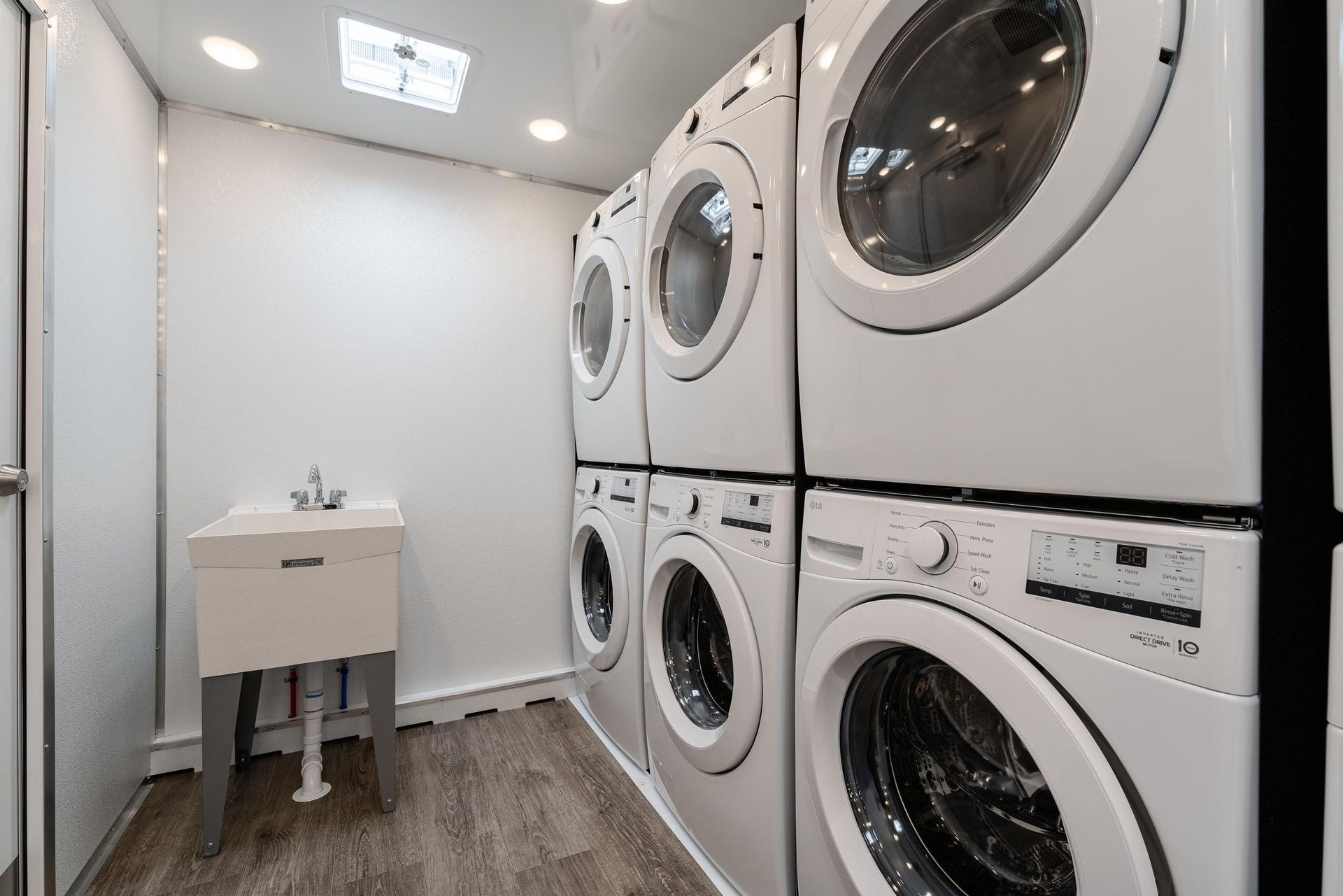 A laundry room with stacked washers and dryers and a sink