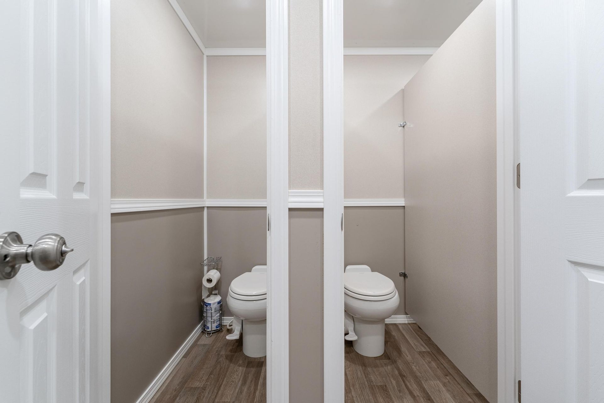 A bathroom with two toilets and a mirror between them
