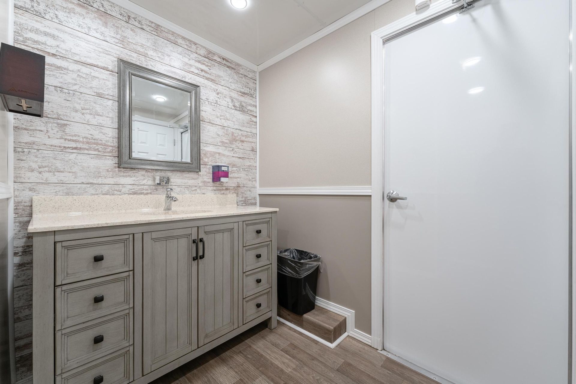 A bathroom with two sinks, a mirror, and a trash can