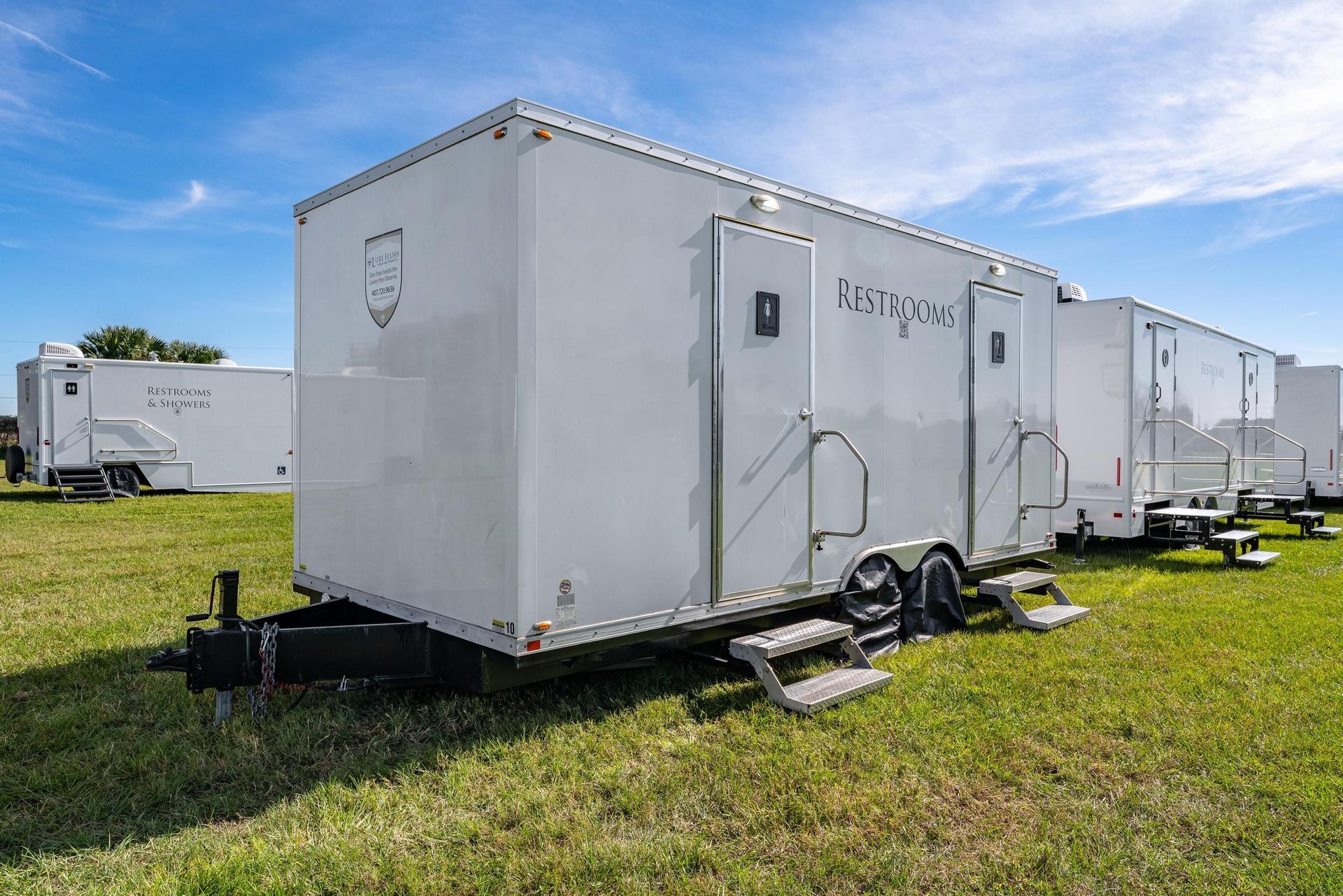 A row of white trailers are parked in a grassy field