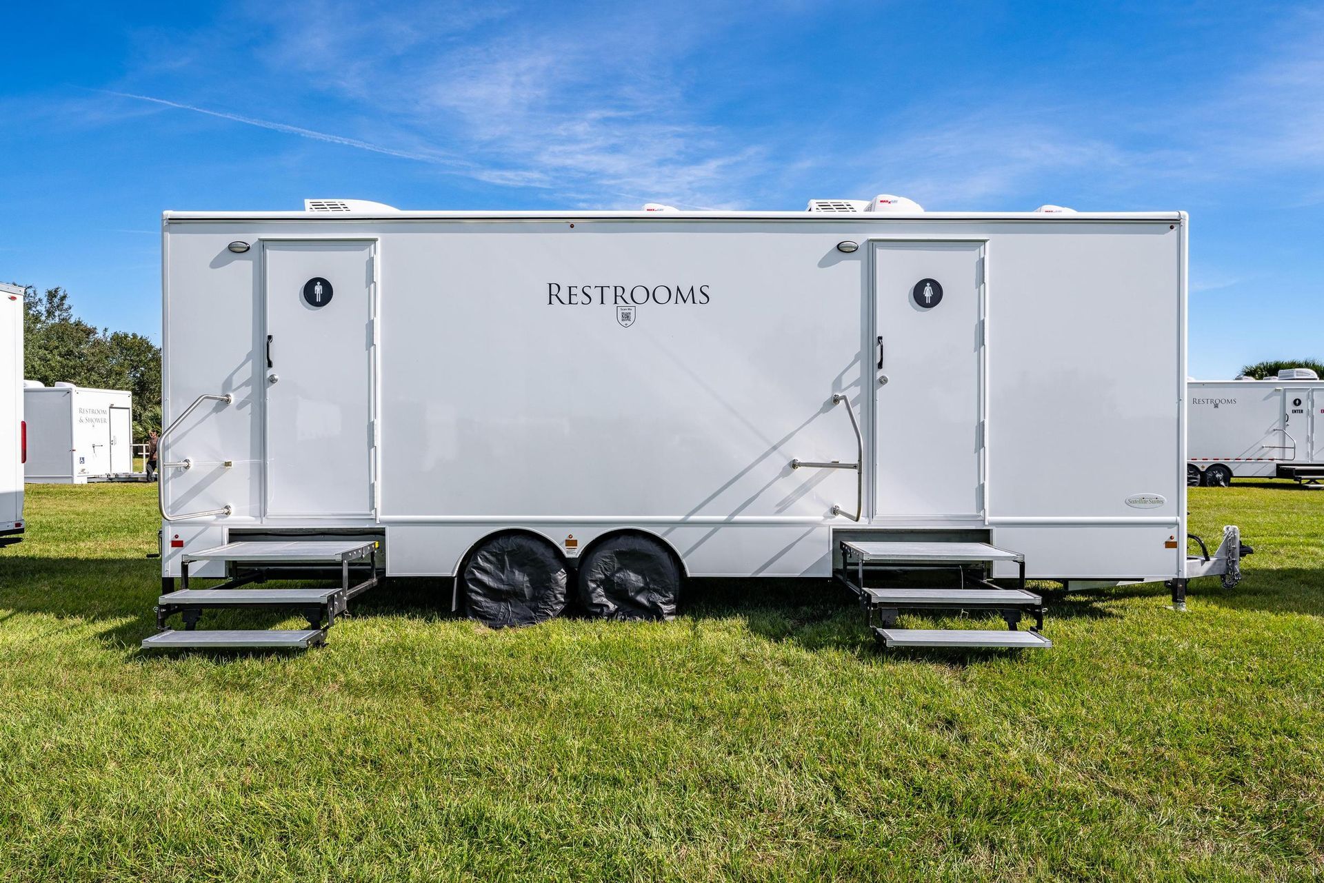 A white trailer is parked in a grassy field