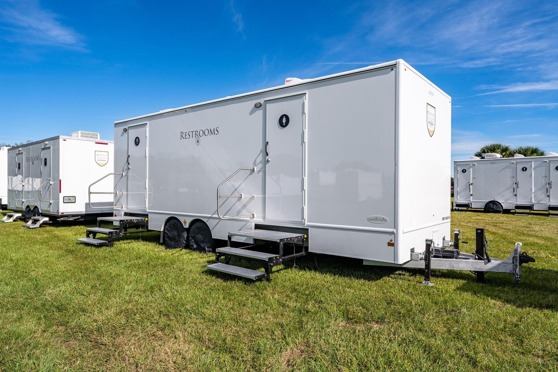 A row of white trailers are parked in a grassy field