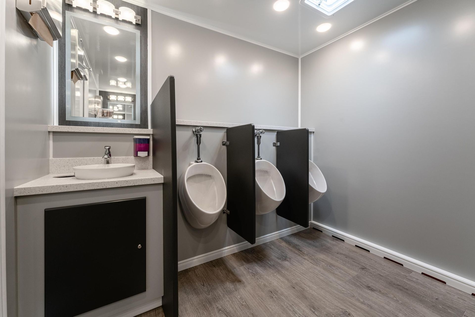 A bathroom with three urinals and a sink
