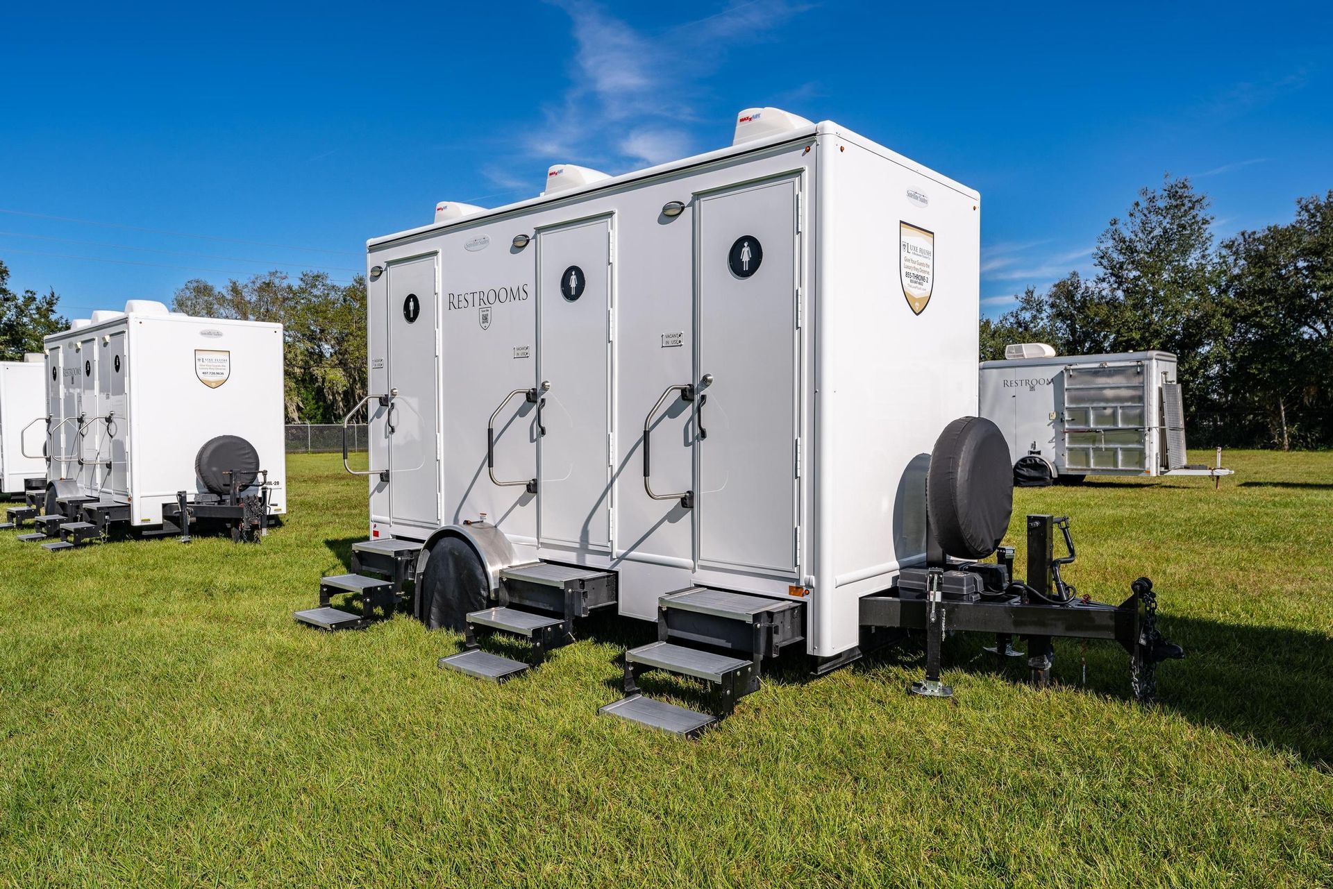 A row of white trailers are parked in a grassy field