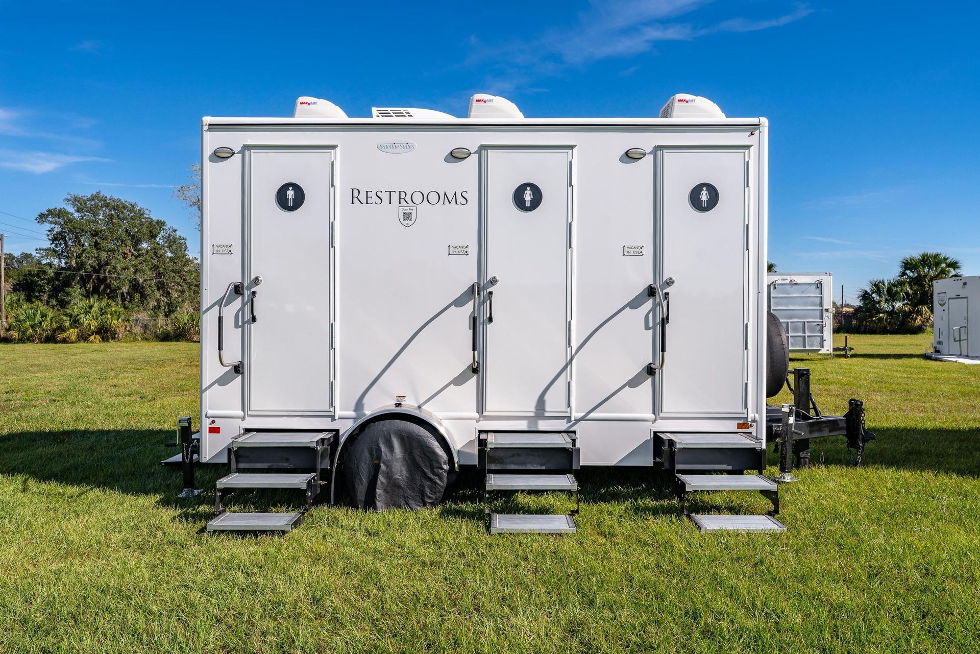 A white trailer is parked in a grassy field