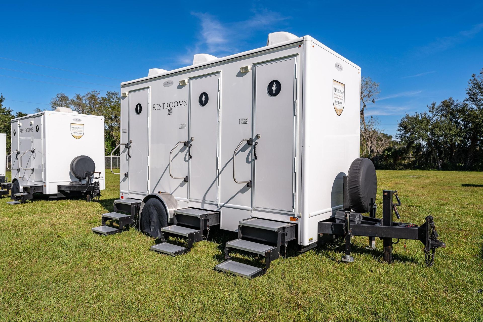 A row of white trailers are parked in a grassy field